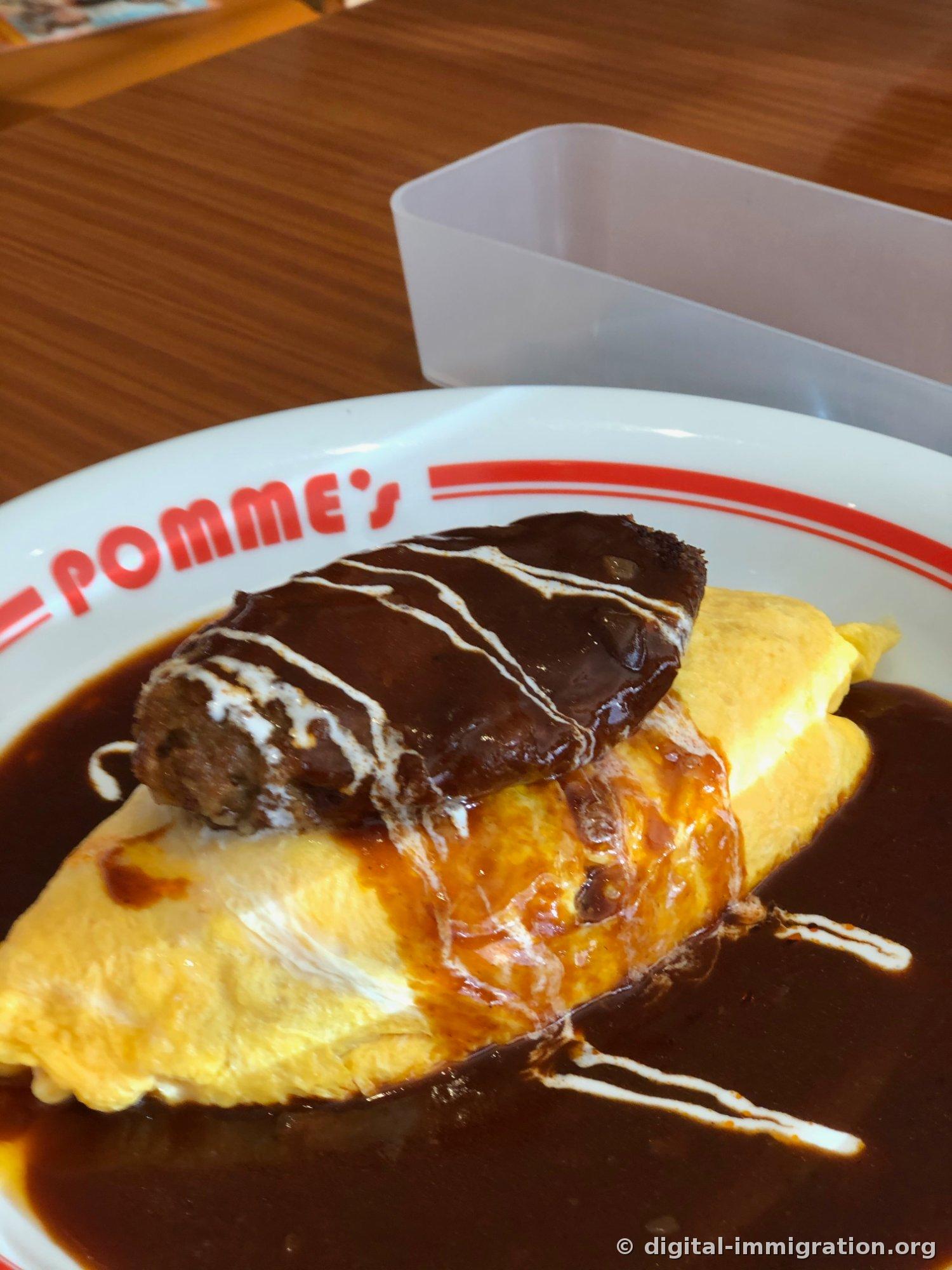 Gros plan bas angle de l'omurice. La section transversale montrant les couches d'œuf superposées et la sauce qui s'écoule est visible