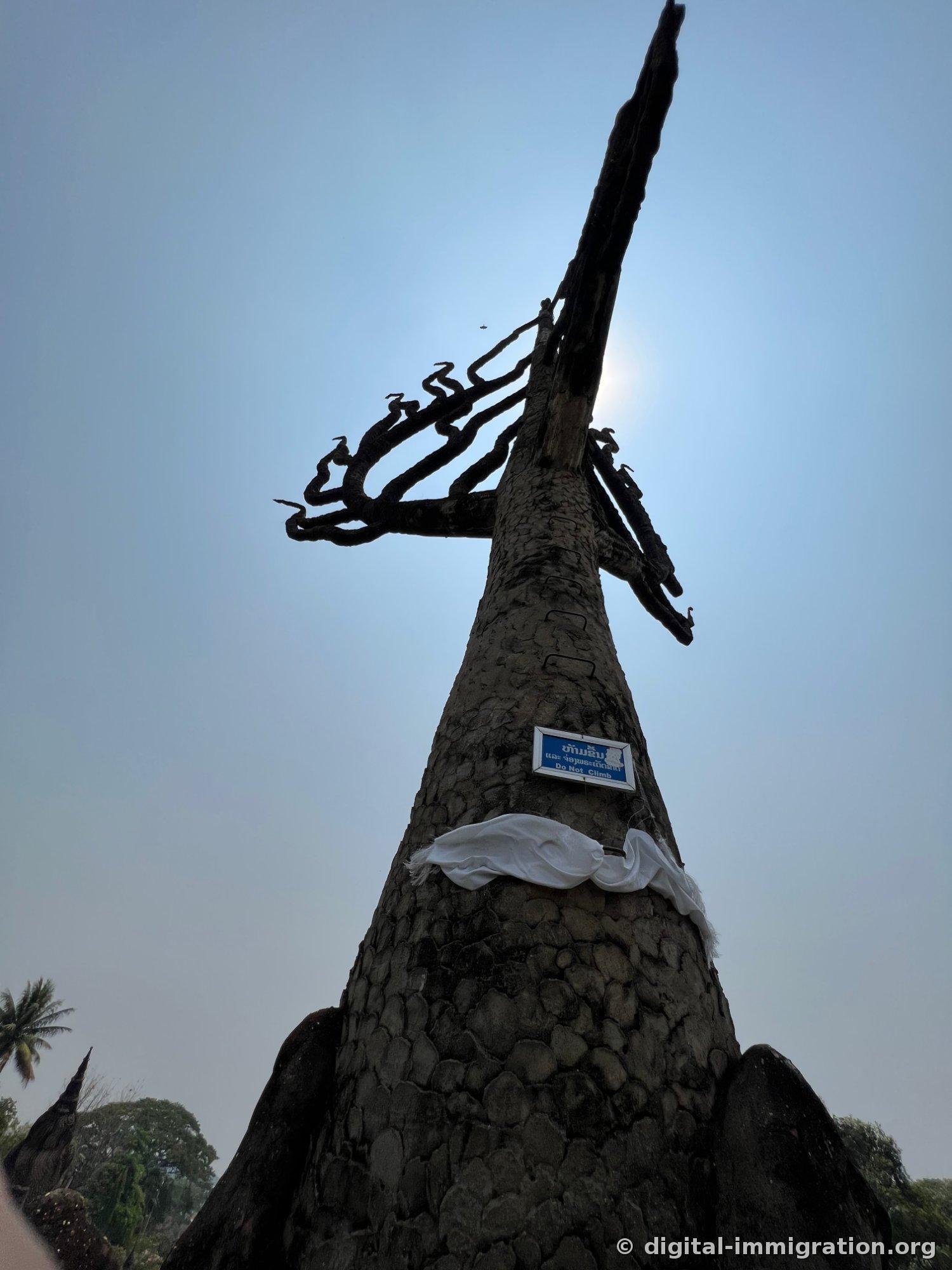 Une formation de naga en silhouette à contre-jour avec une pancarte bleue « Do Not Climb » et du tissu blanc enroulé autour du corps