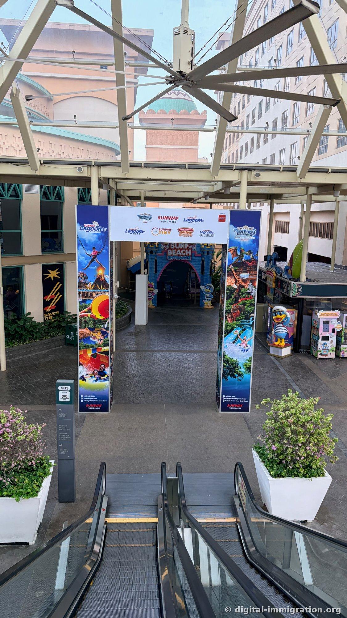 从电扶梯上看到的 Sunway Lagoon Surf Beach 入口大门和 SB3 BRT 指示柱、主题公园宣传横幅
