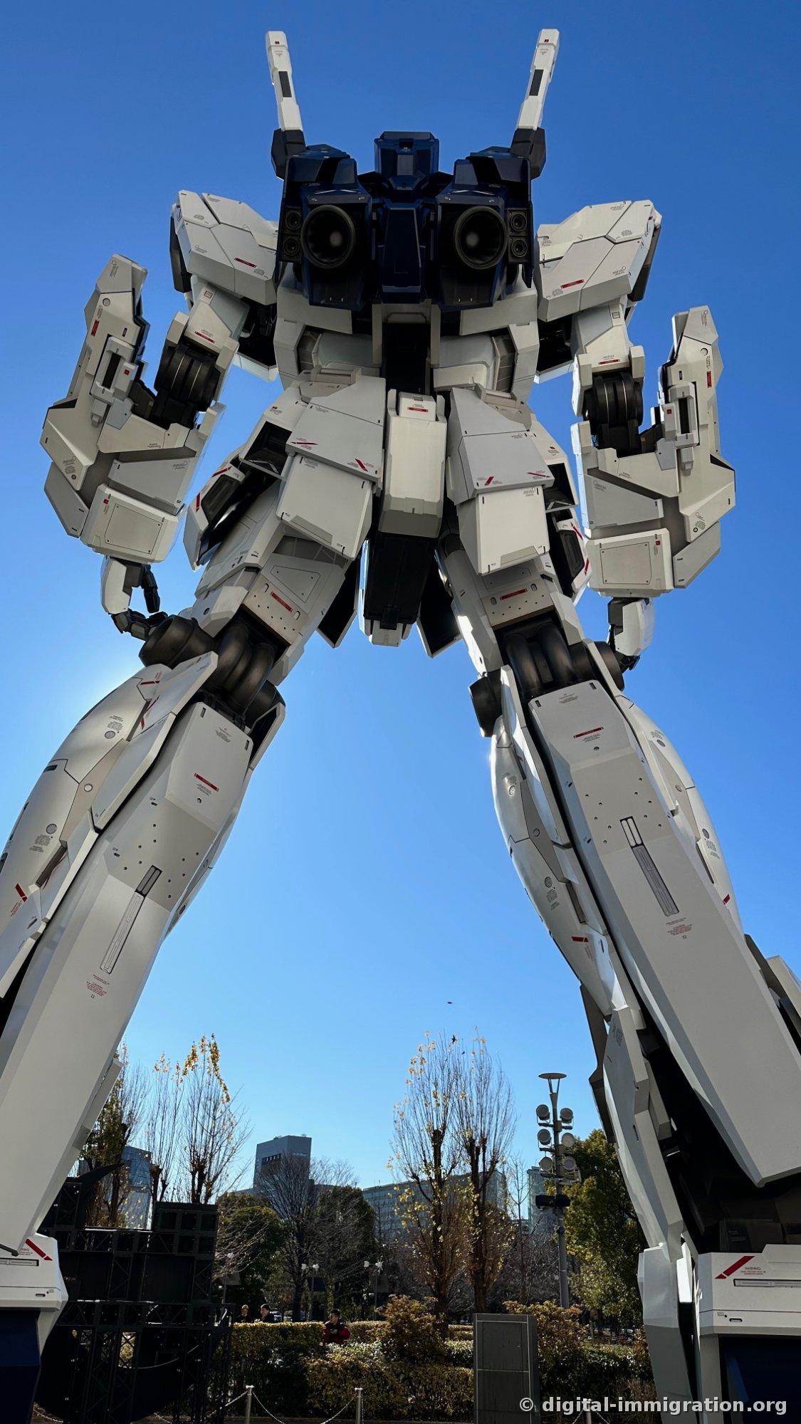 The Unicorn Gundam viewed from directly below, its horns split into two, with the black speaker on the shoulder and opened armor panels visible in Destroy mode