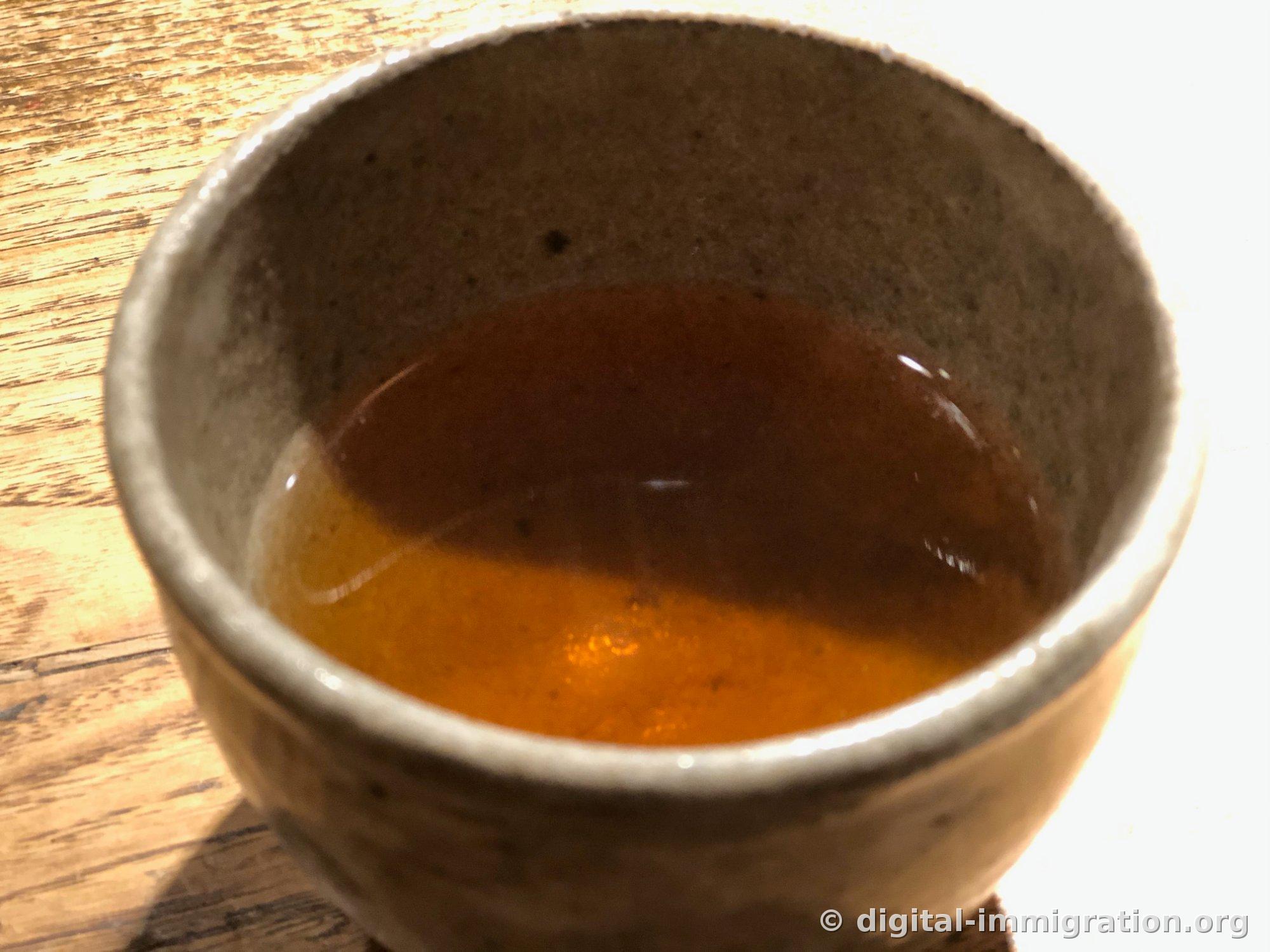 거친 질감의 도기 찻잔 안에 담긴 진한 갈색 차를 위에서 내려다본 모습