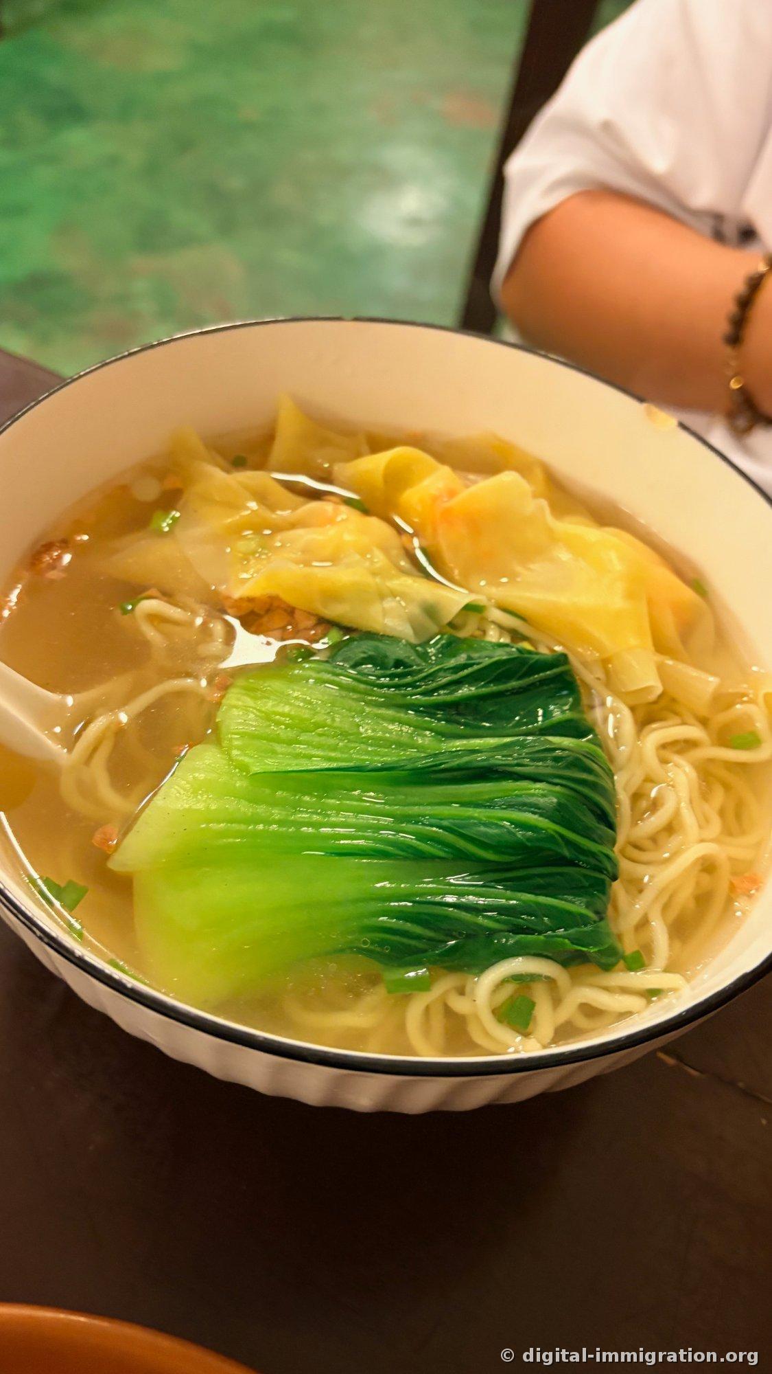 透明なスープに黄色い皮のエビのワンタンが数個と細い麺、青菜1本が丸ごと入ったワンタン麺1杯