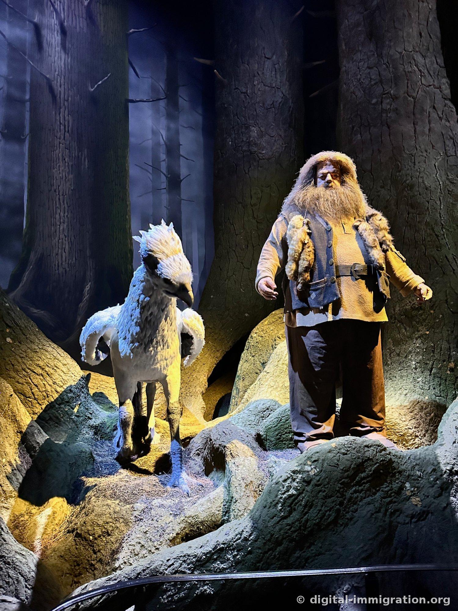 A white hippogriff (Buckbeak) and a Hagrid figure standing in a dark forest set with moss-covered rocks