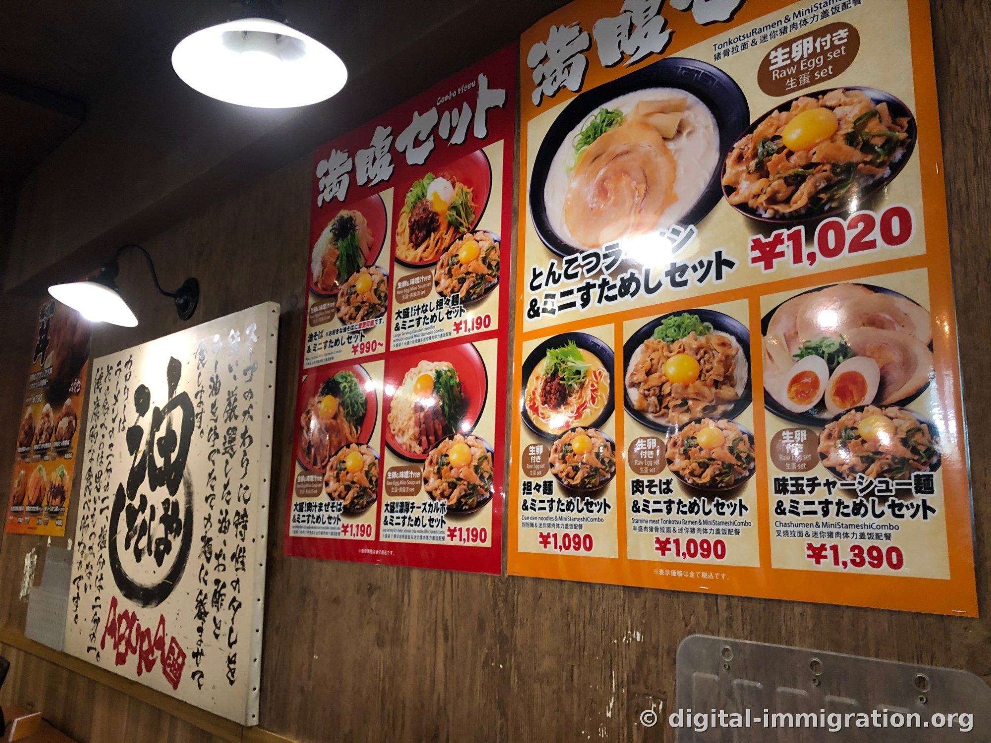 Deux affiches de menu de set 満腹セット accrochées au mur du restaurant et à gauche une enseigne en bois avec des caractères manuscrits 油そば