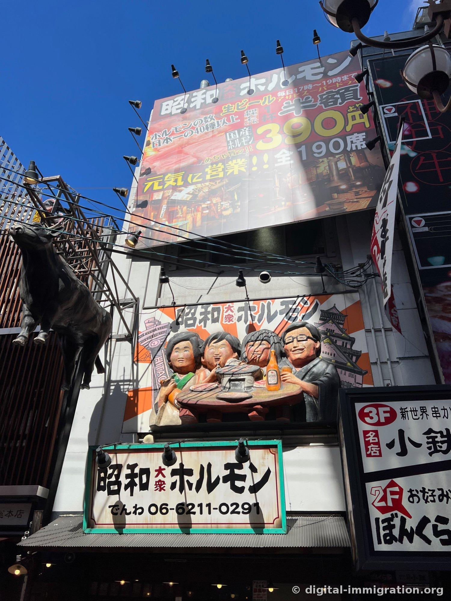 L'enseigne Showa Daishu Horumon avec un tableau disant horumon japonais 390 yen, place assise 190, et une statue de vache noire