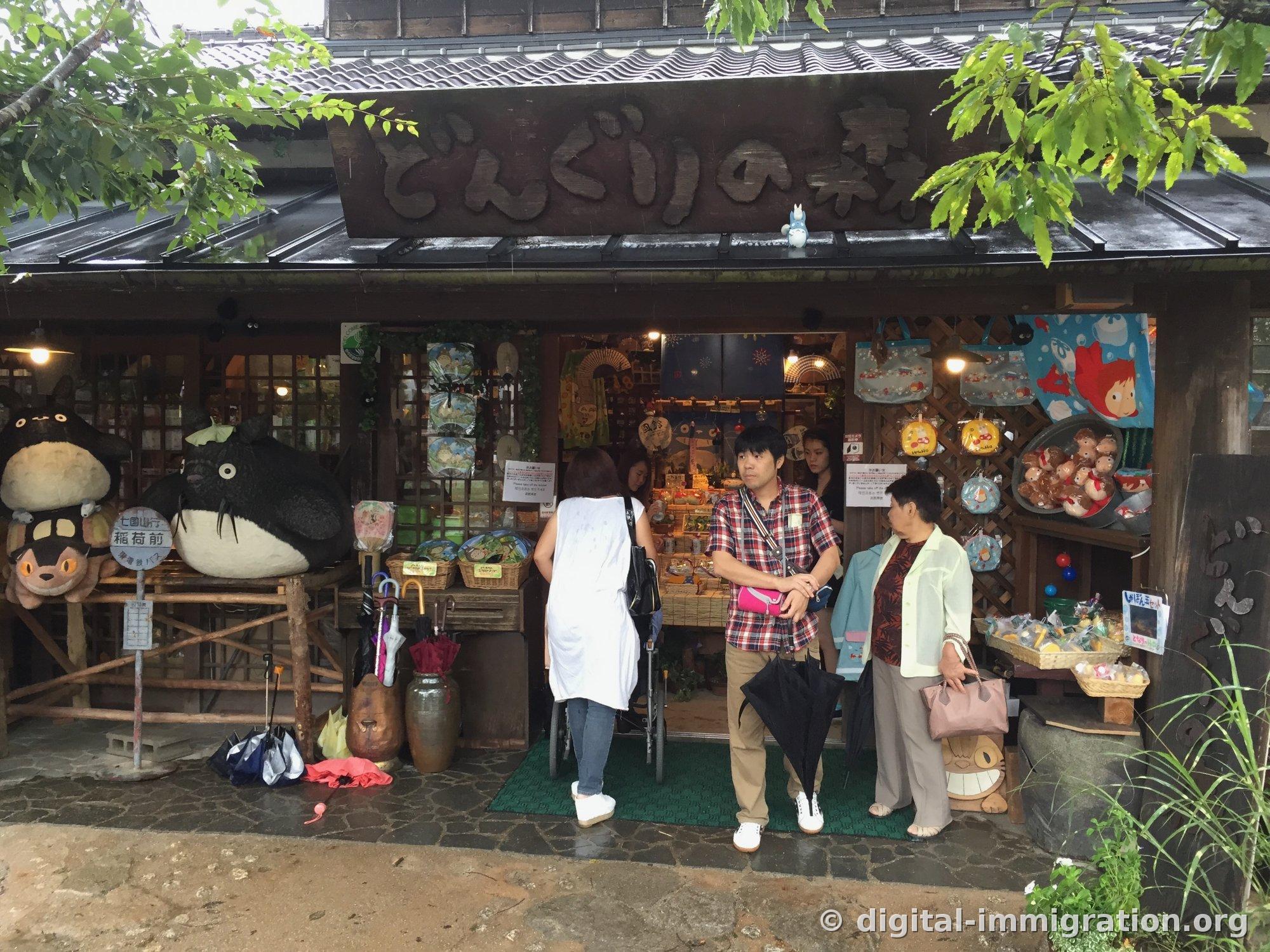 La devanture de どんぐりの森 avec un grand Totoro et un Chat-Bus, avec des clients devant sous un panneau en bois