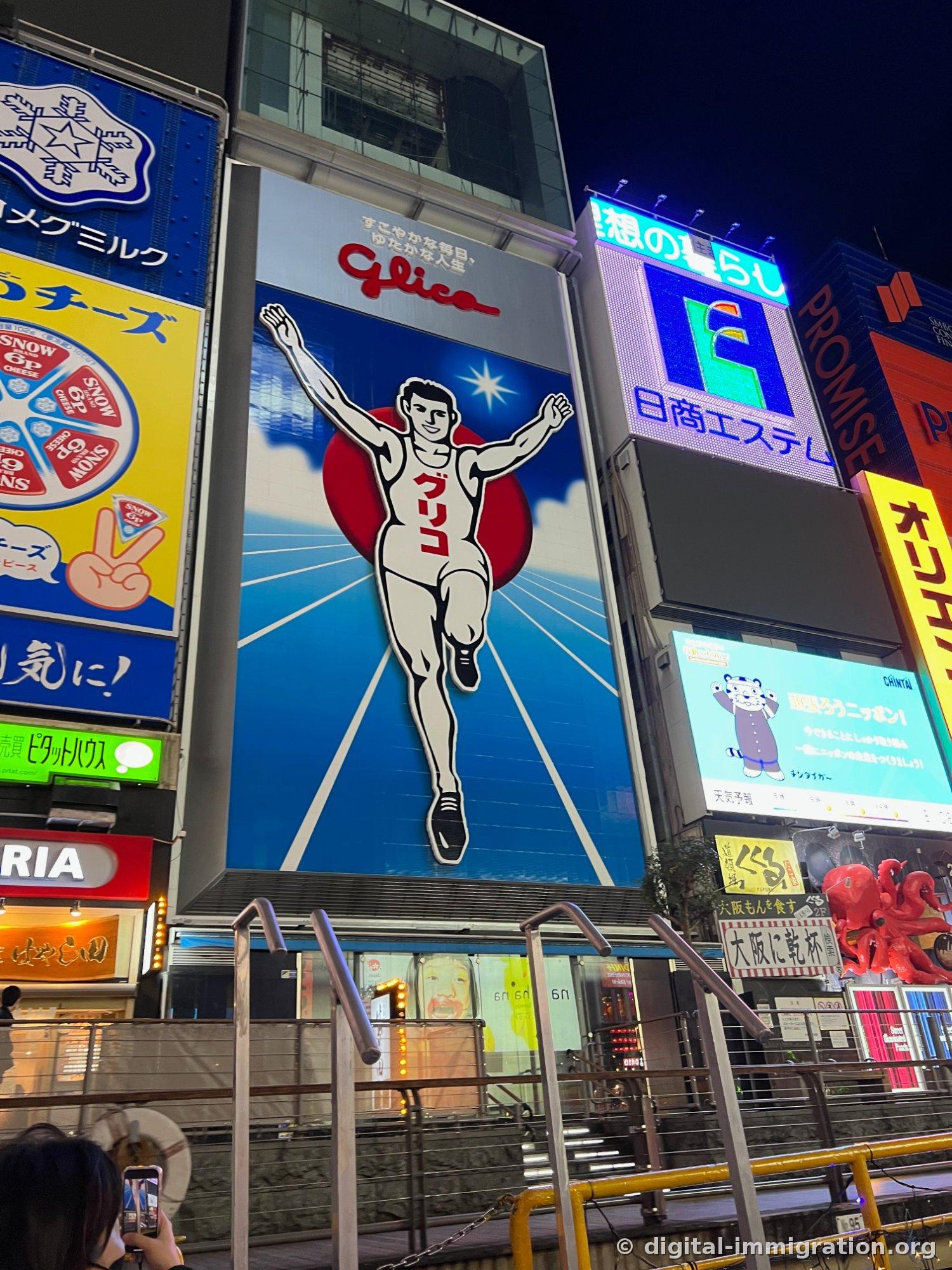 Enseigne Glico coureur illuminée la nuit, des gens prenant des photos sur les escaliers en dessous