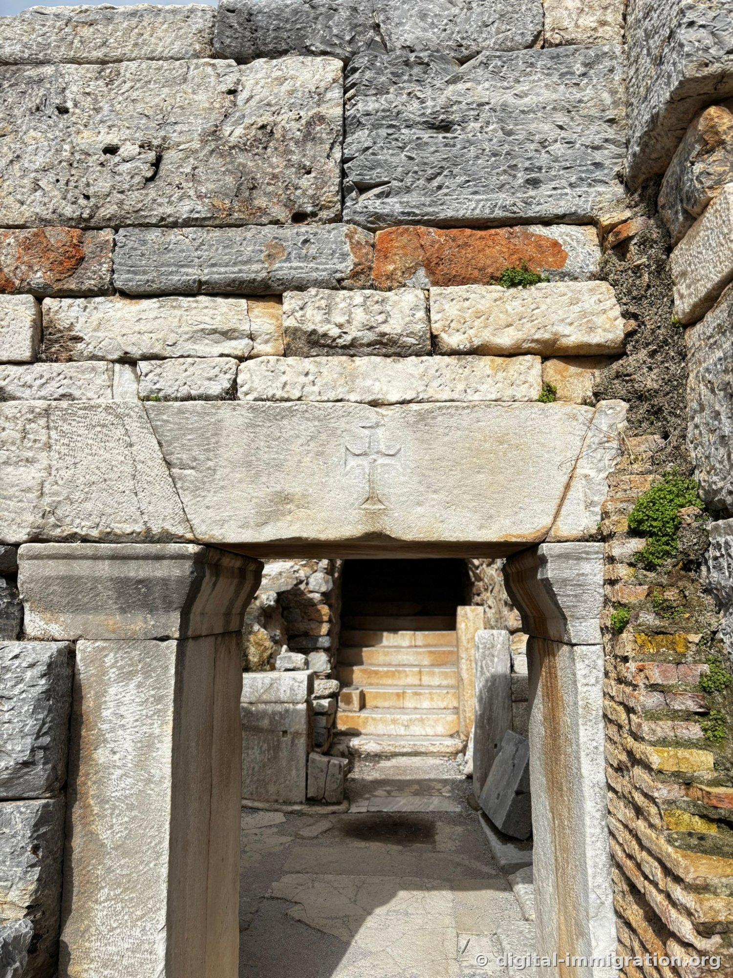 A white marble slab beneath a wooden deck with a six-sectioned wheel and Greek letters drawn in red, along with a fish shape
