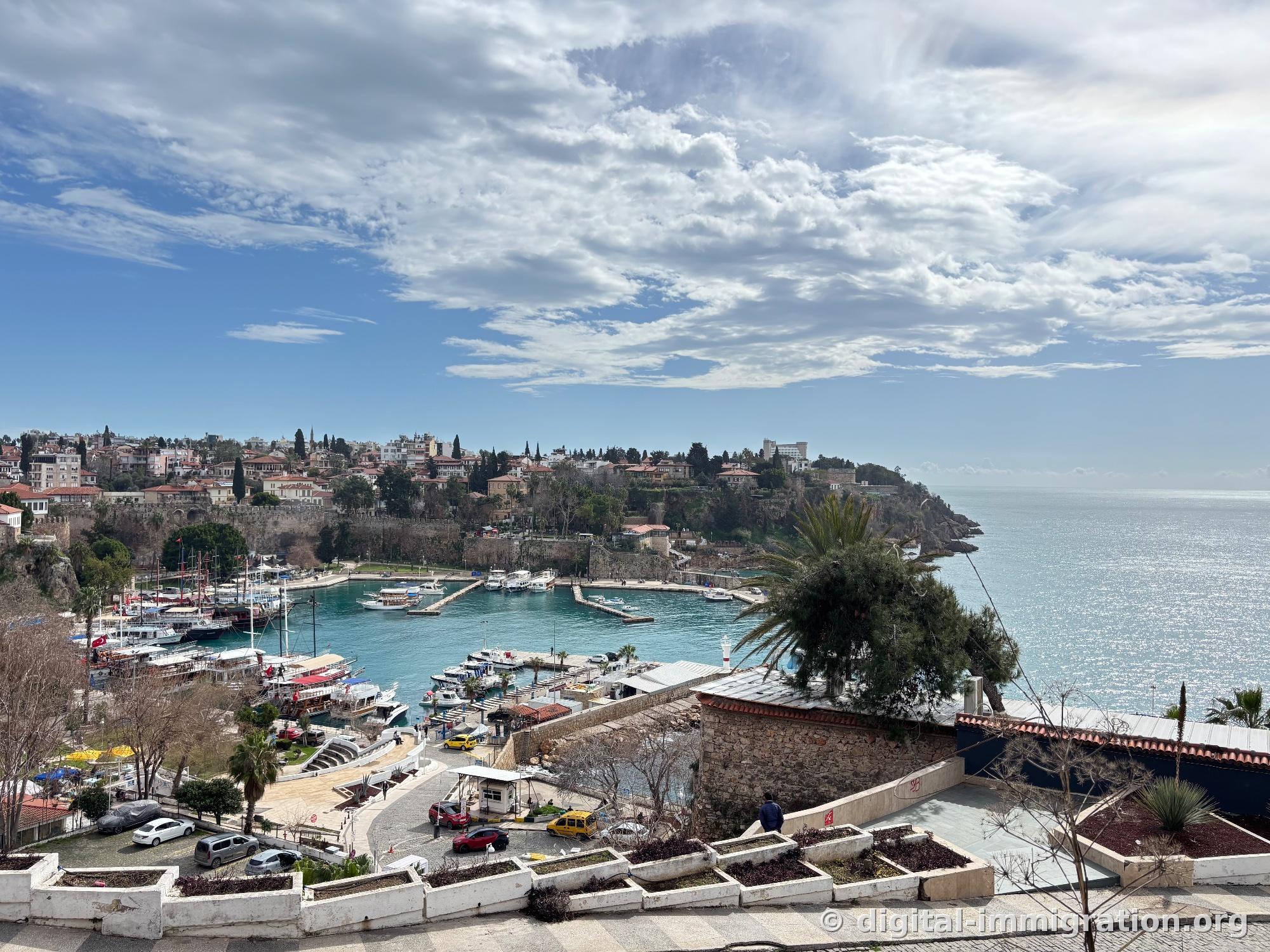 Panoramic view of Kaleici city walls and old town tile-roofed houses, wooden sailboats moored in the jade bay below