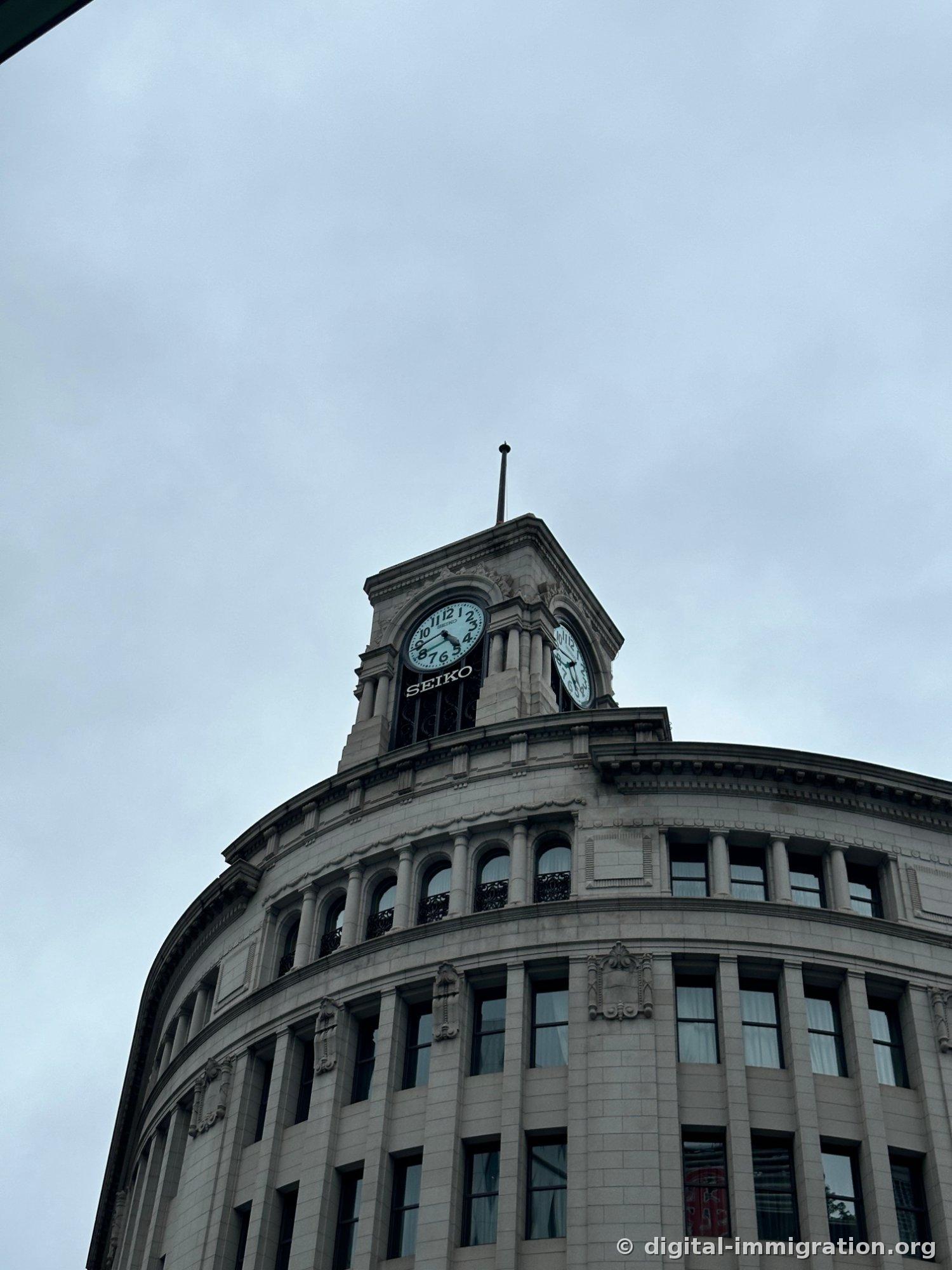 Close-up of Seiko clock tower against gray sky, SEIKO text visible below clock face