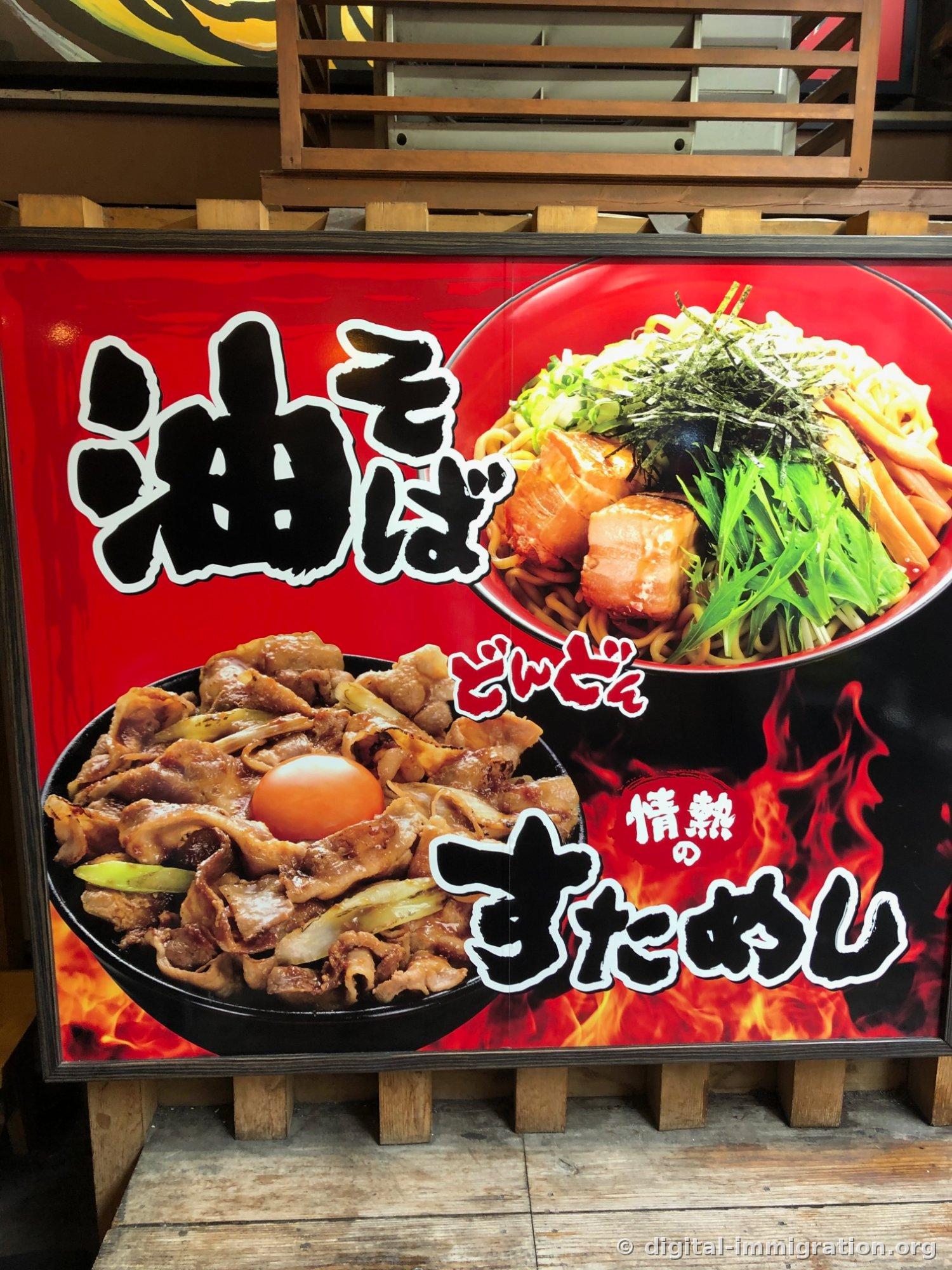 Panneau publicitaire en bois à cadre rouge à l'avant du magasin avec le texte 油そば et une photo de nouilles sans bouillon, en bas avec une grande photo de riz garni de viande avec jaune d'œuf