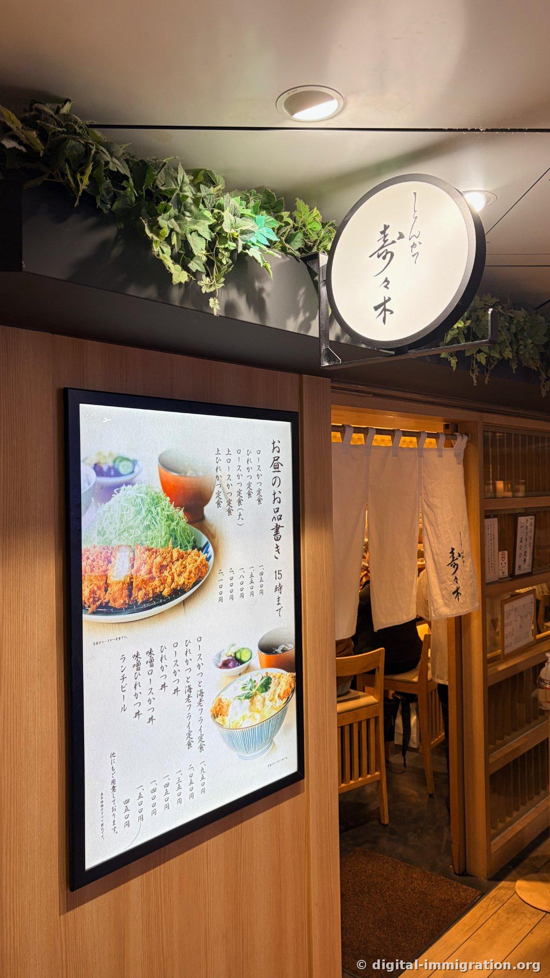 圆形'寿々木'招牌灯和午餐菜单灯箱挂在店铺入口，白色暖帘后能看到木椅和顾客
