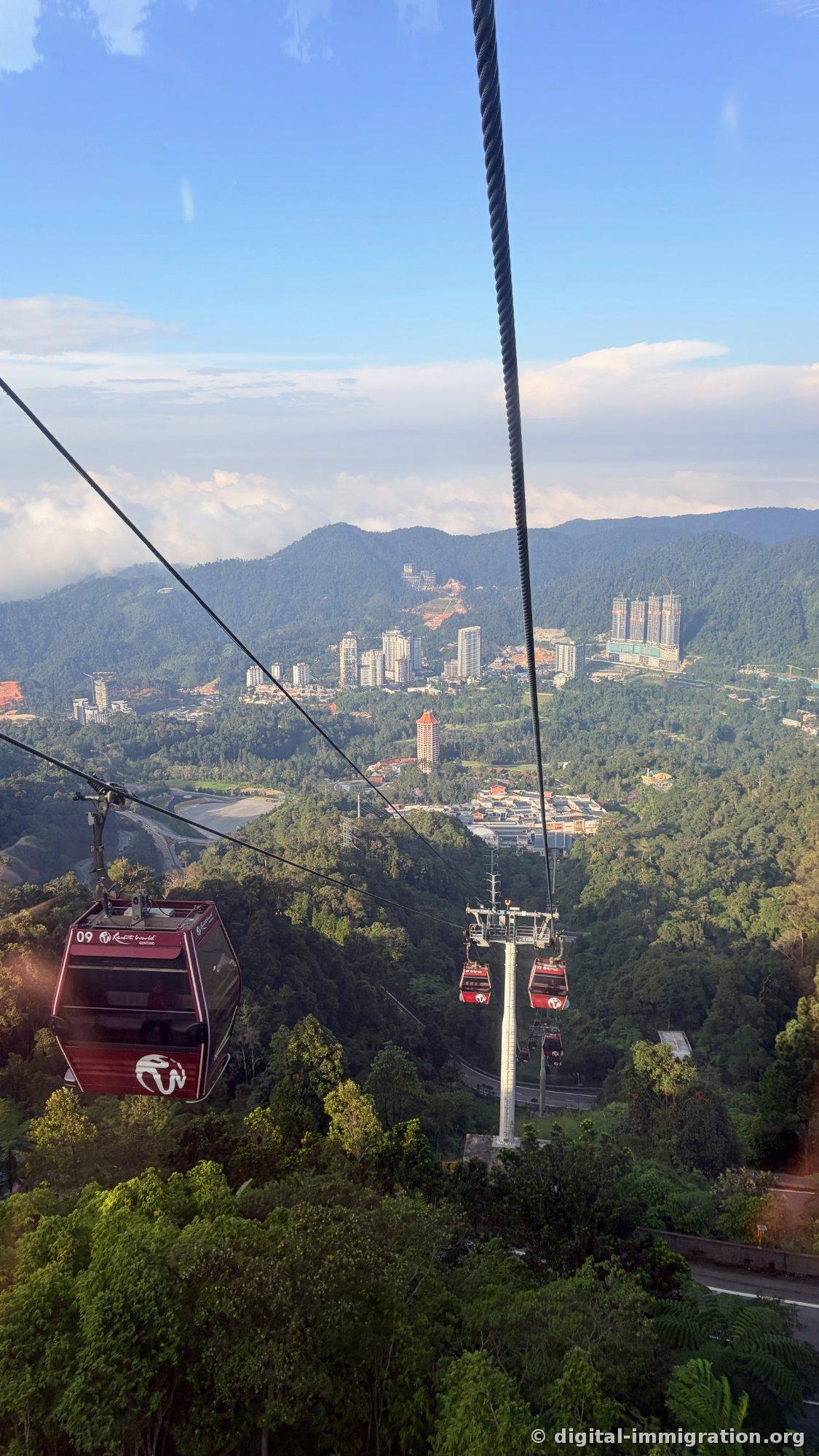 Panoramic view of Genting cityscape from cable car with cabin 09 and mountain-ridge high-rises, cloud layer visible below