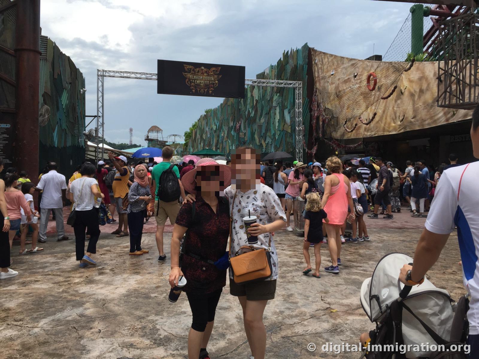 Afternoon scene of an outdoor corridor with the TERROR-COTTA EMPRESS sign, crowded with tourists holding parasols and umbrellas for sun protection