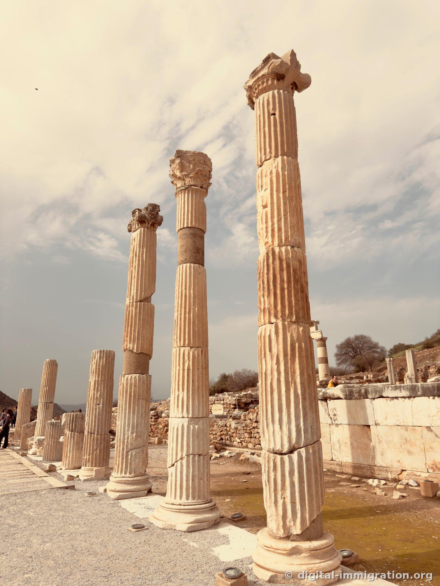 Marble columns with grooved channels lined in a row with water pooled on the ground in the State Agora area