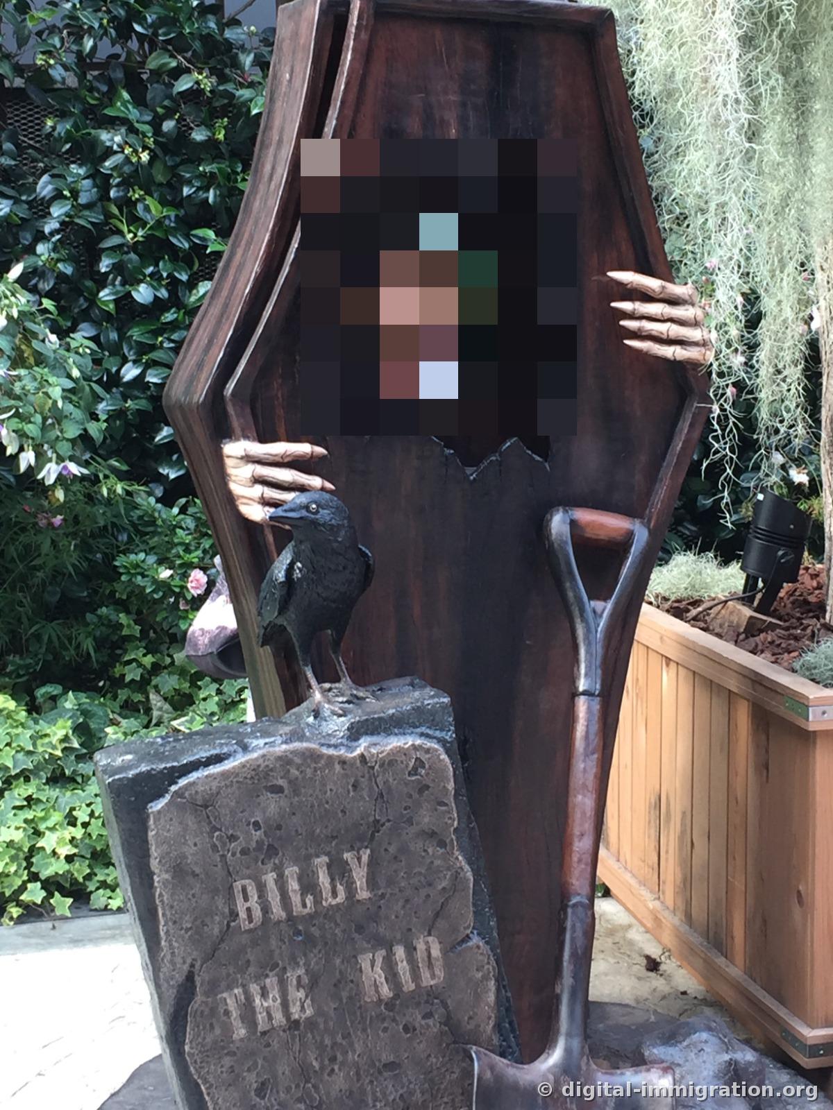 A tombstone engraved BILLY THE KID and a coffin with a hand sticking out, with a raven perched on top creating a Halloween photo spot