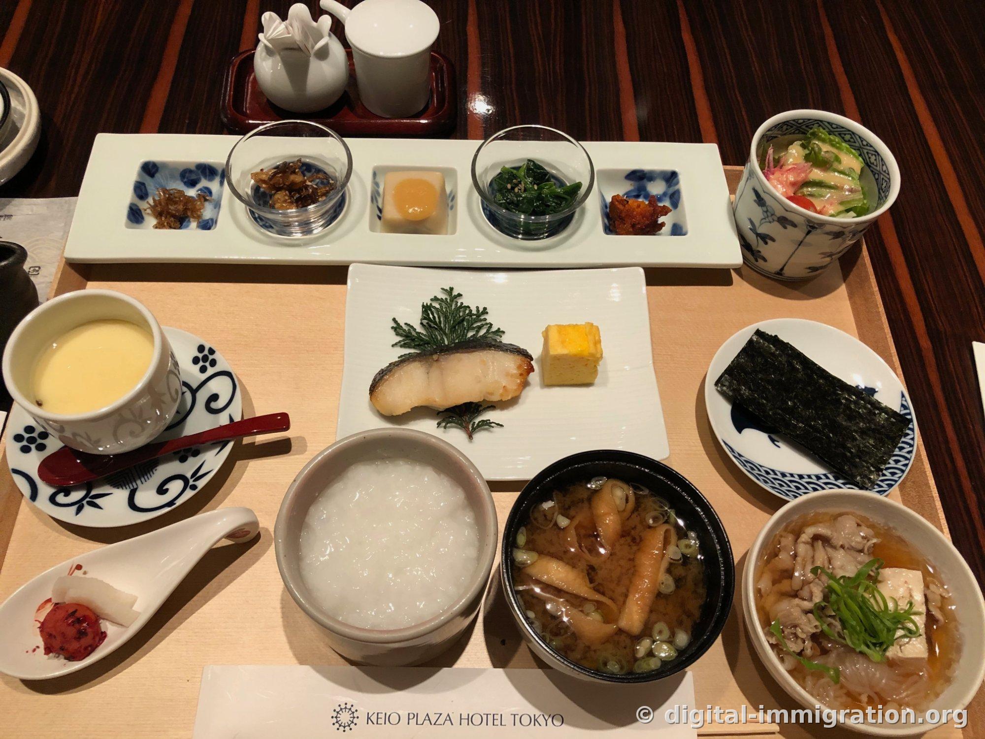 Plateau de petit-déjeuner Kagari complètement ouvert. Le porridge blanc, la soupe miso avec tofu frit et oignons verts, le nikou-dofu avec porc et tofu braisés, le chawan-mushi jaune, le poisson blanc grillé et l'omelette roulée sont tous visibles