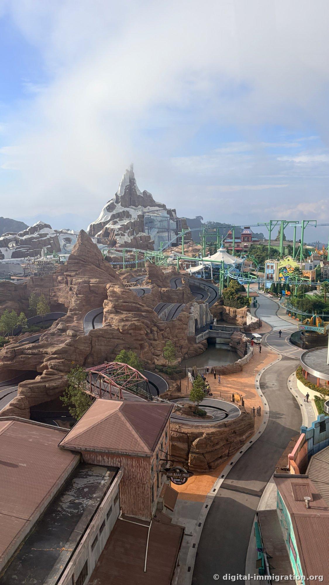 Overhead view of Genting SkyWorlds showing snow-covered artificial peak, red sandstone canyon track, and green roller coaster rail