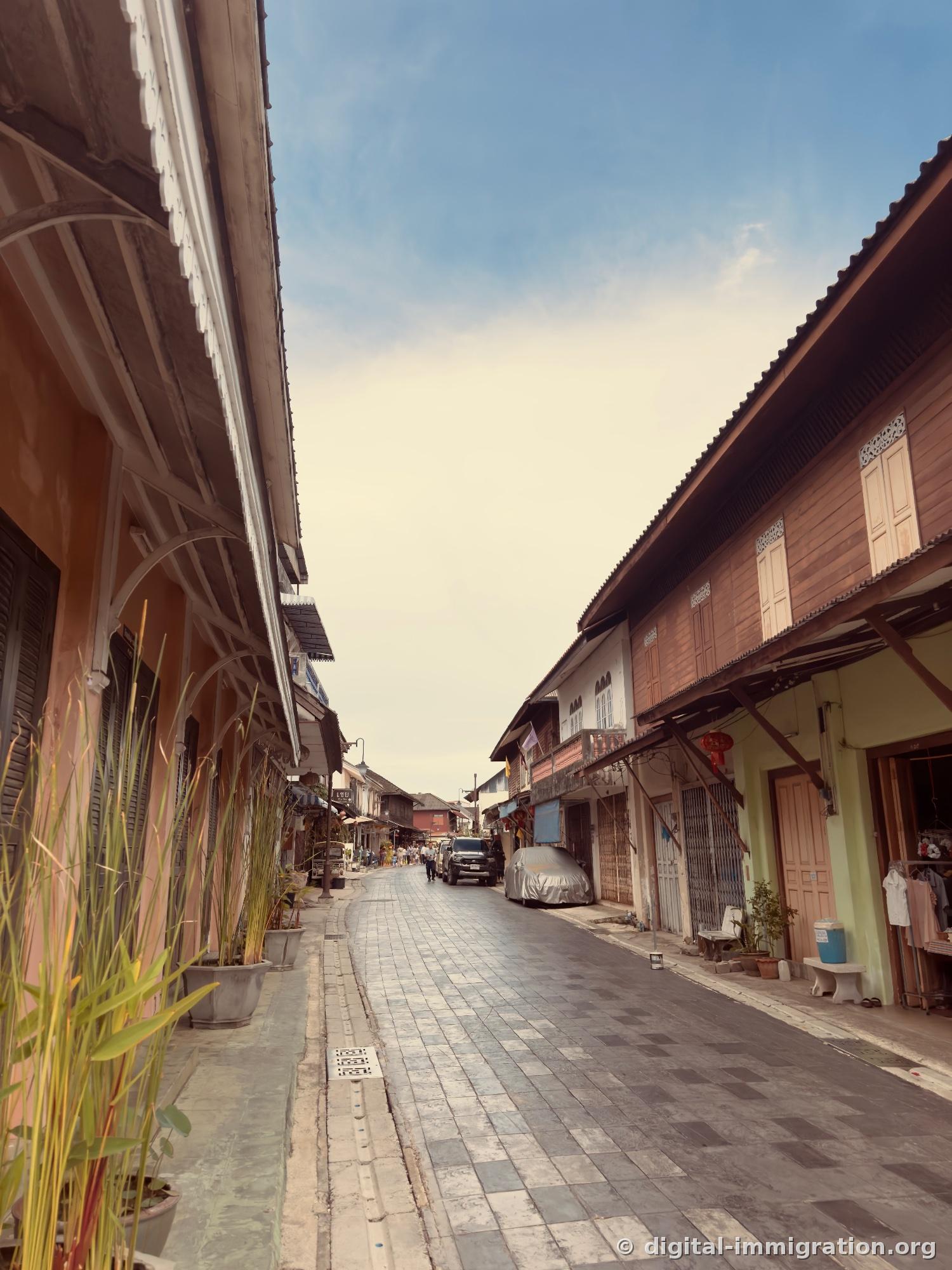 Overview of Yomjinda Road with gray tiles, wooden two-story shops on both sides and blue sky