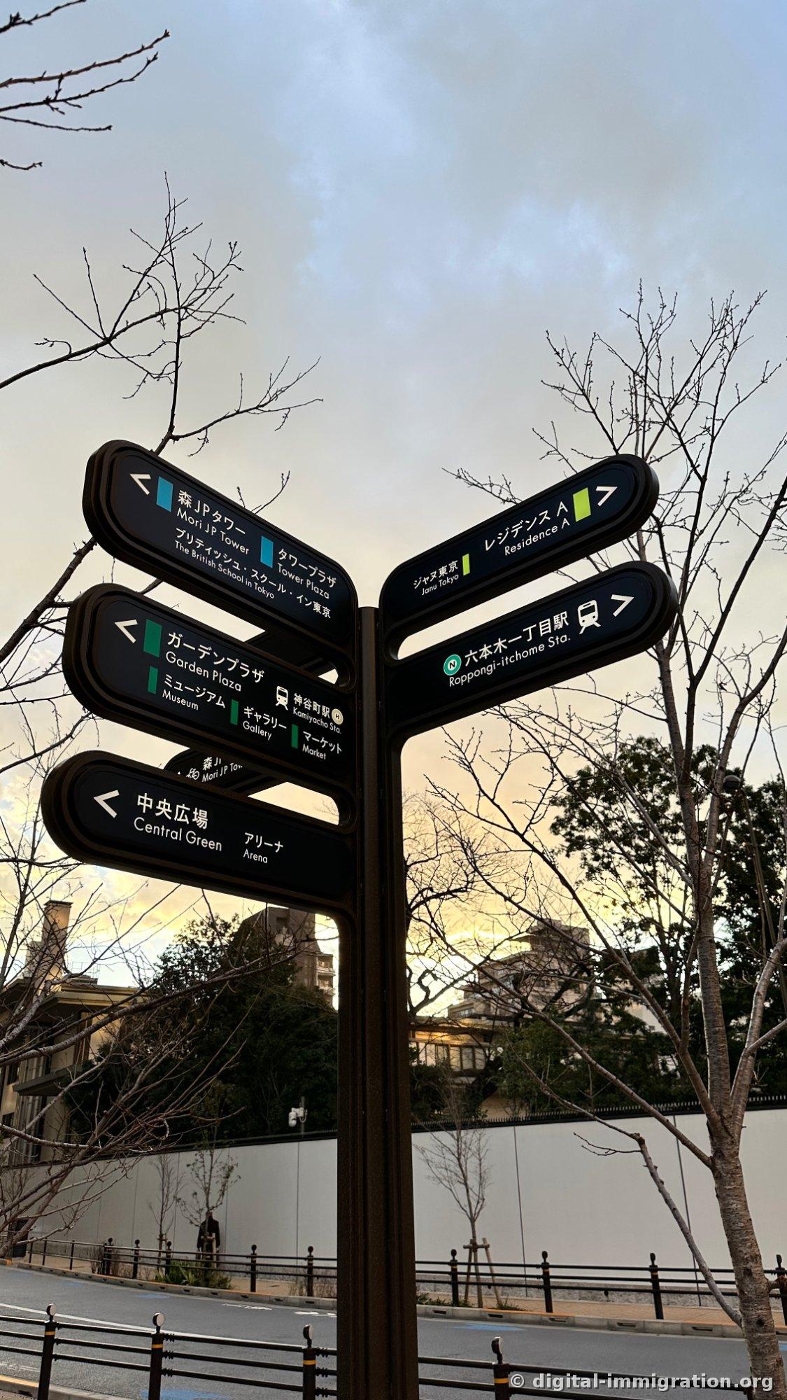 Azabudai Hills outdoor directional sign showing arrows to Mori JP Tower, GardenPlaza, Central Plaza, and Roppongi-itchome Station