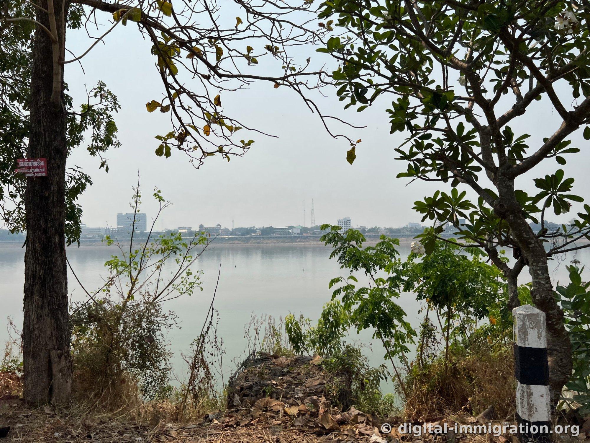 Le Mékong vu à travers les arbres et les bâtiments thaïlandais de l'autre côté avec un ciel brumeux