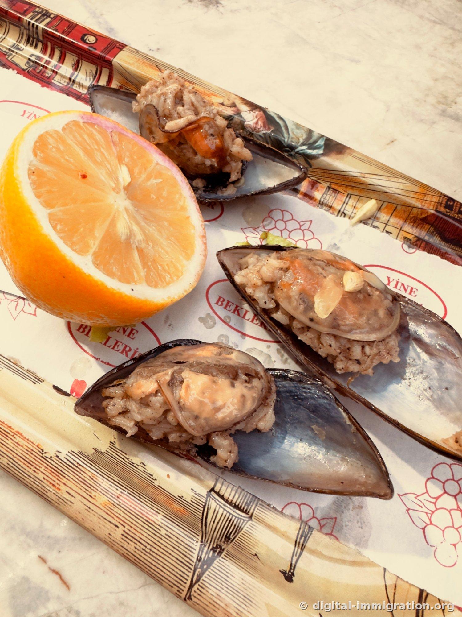 Three mussel rice and half-cut lemon on paper on a marble table, rice mixed with pine nuts