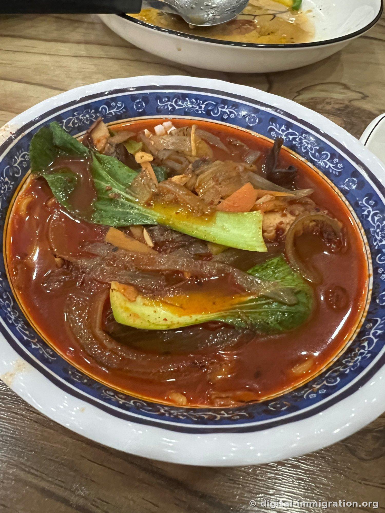 Jjamppong served in a blue-patterned bowl. Broth and vegetables remaining after the noodles are eaten.