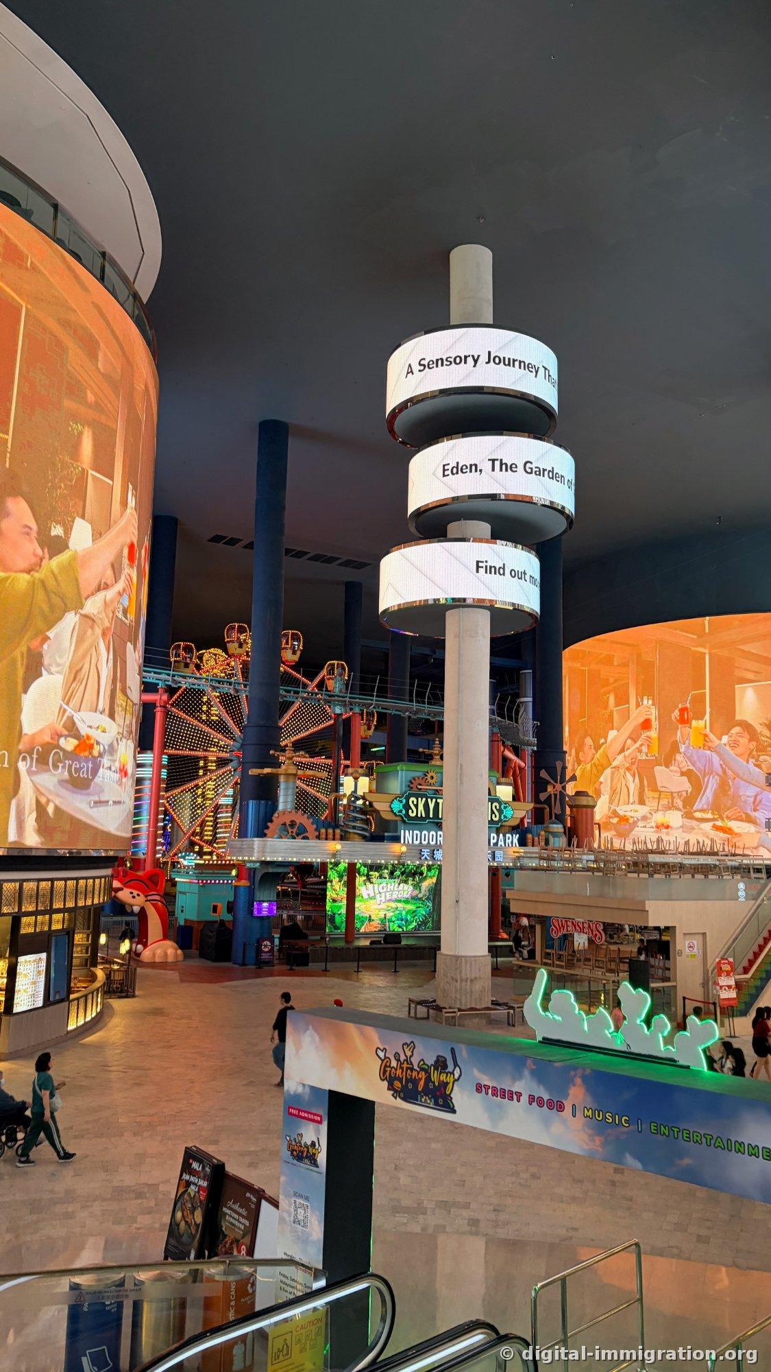 Indoor plaza cylindrical LED showing A Sensory Journey and Eden The Garden of text with SKYTROPOLIS sign and Gohtong Way street food banner below