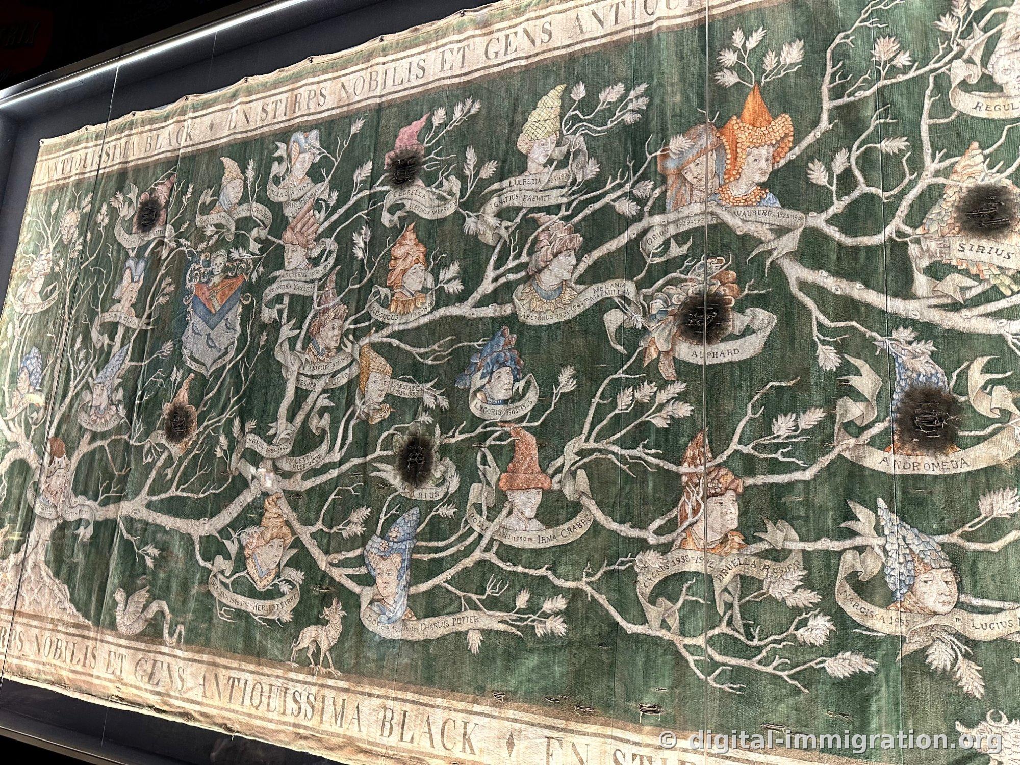 A tapestry showing a family tree with silver branches, faces, and name ribbons on a dark-green background, with some sections scorched and torn