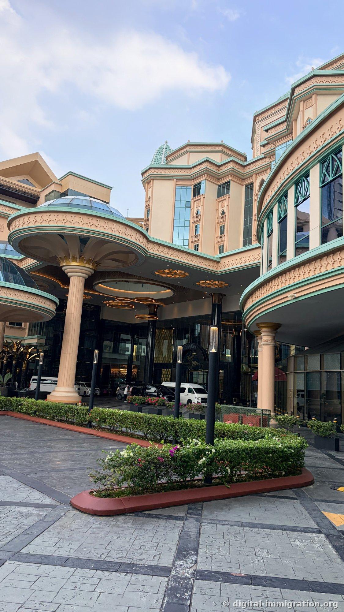 杏色外墙和青绿色屋顶、蘑菇形大型雨棚的 Sunway Resort Hotel 正门进入路和花坛