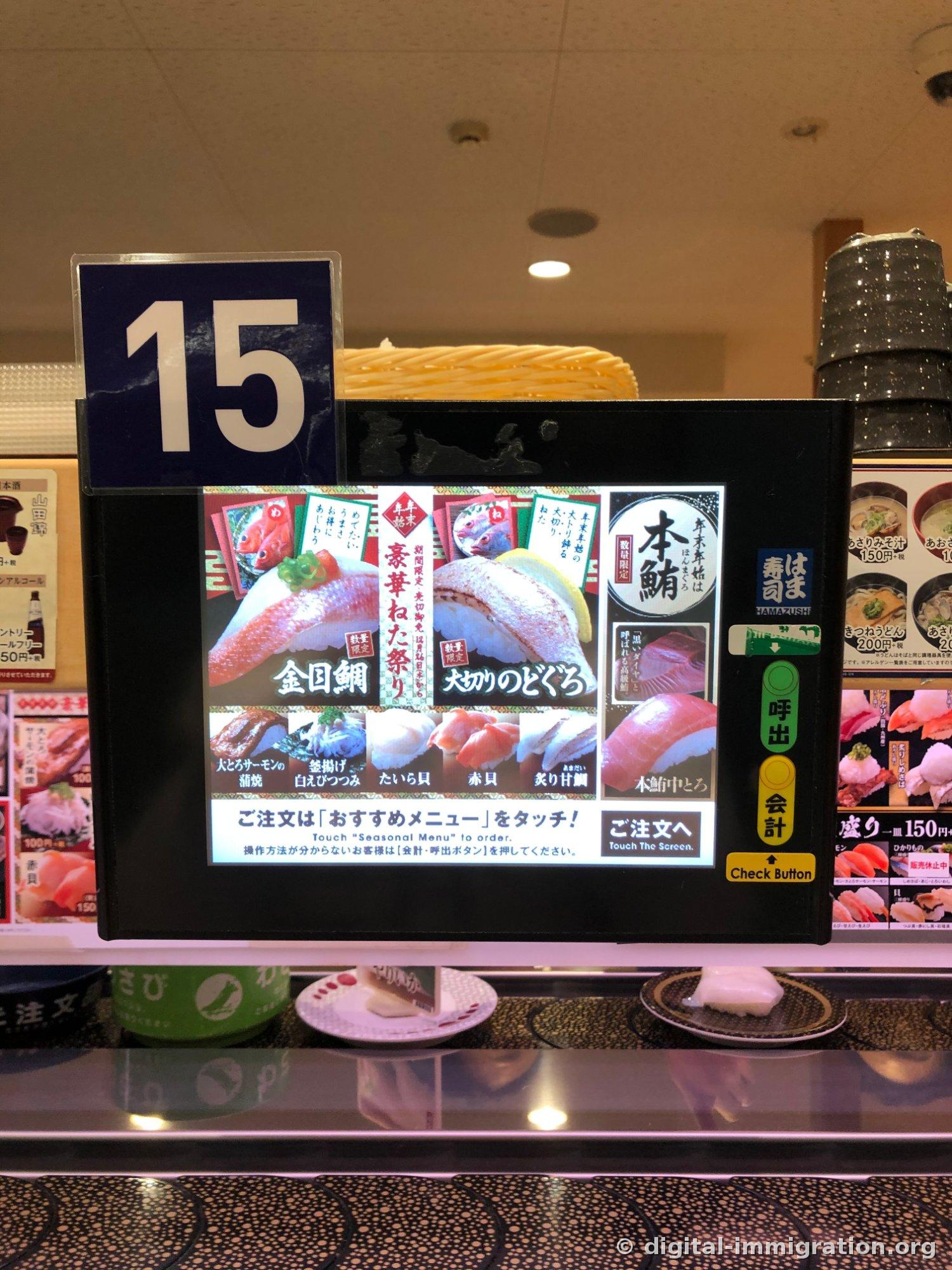 Sur le panneau tactile sous la plaque de siège numéro 15, le menu limité de fin d'année comme le kinme-dai, le blackthroat épais et le ventre moyen de thon blanc est affiché, avec des boutons d'appel et de paiement à côté