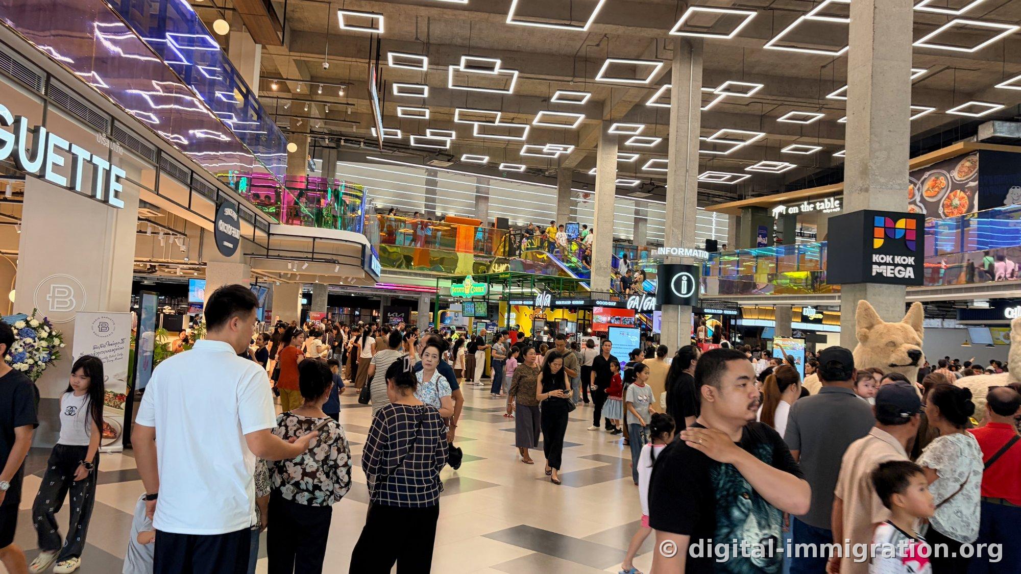Crowded ground floor central hall with Paris Baguette sign on left and KOK KOK MEGA signage in center, white dog mascot on right