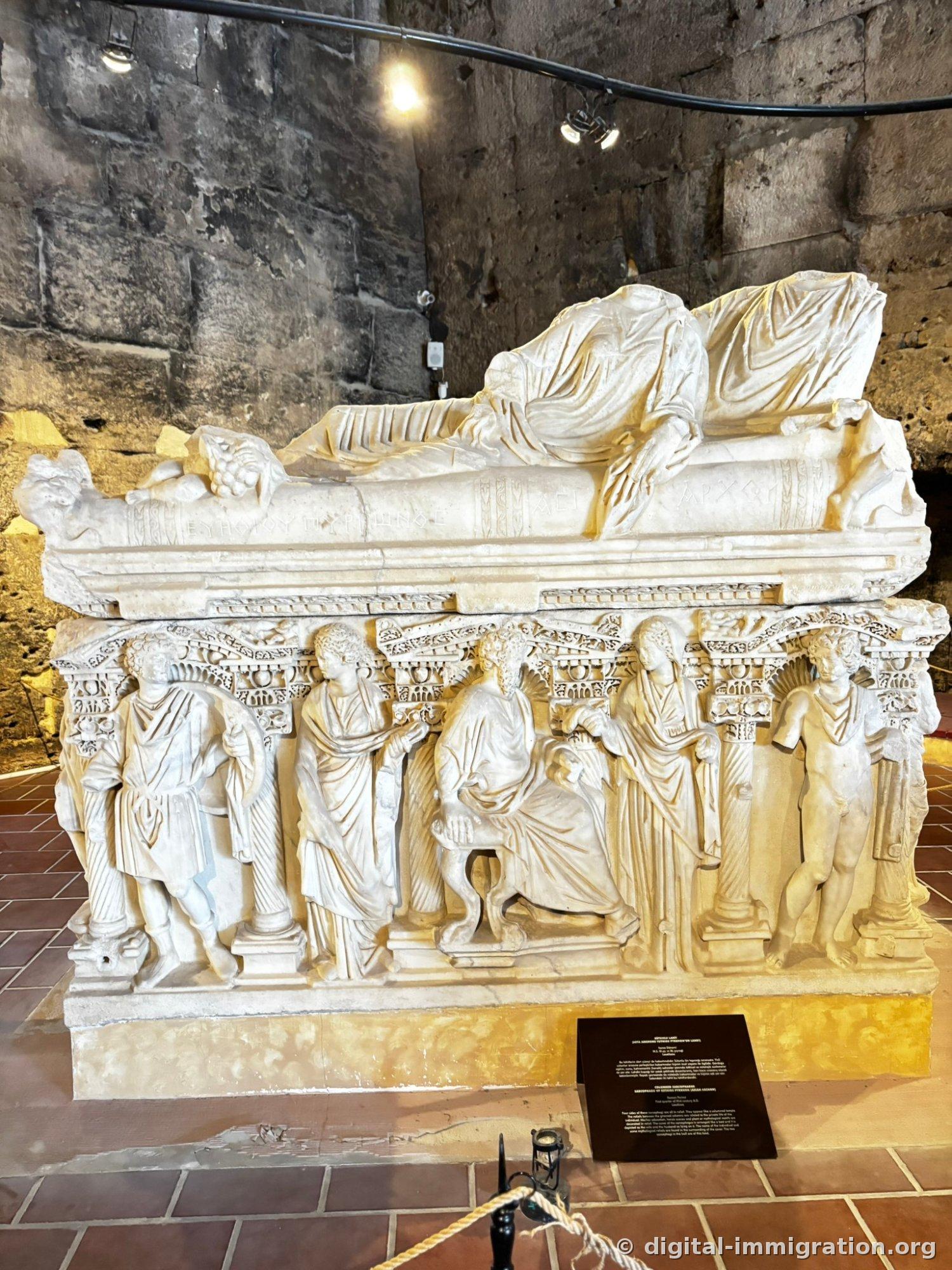 Large marble sarcophagus with two reclining figures carved on the lid appearing to be a couple, relief figures carved between columns on all four sides of the body