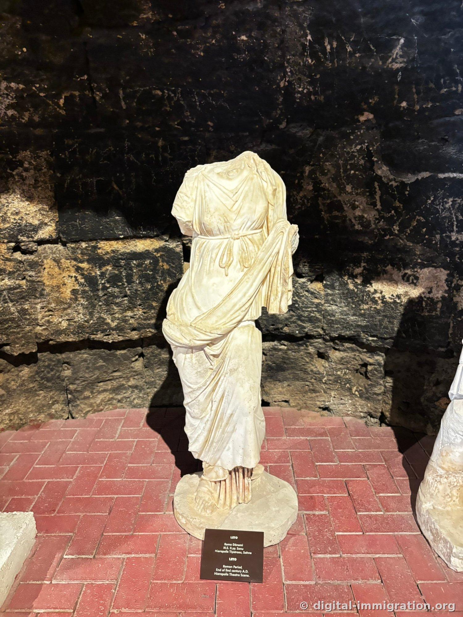Headless statue of goddess Leto with tied belt at waist and draped shawl folds flowing from shoulders clearly preserved