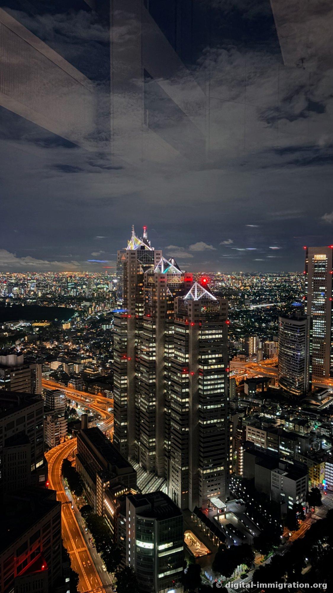 Les trois toits triangulaires du Park Hyatt Tokyo illuminés et la rampe d'accès de l'autoroute qui s'écoule vers le bas