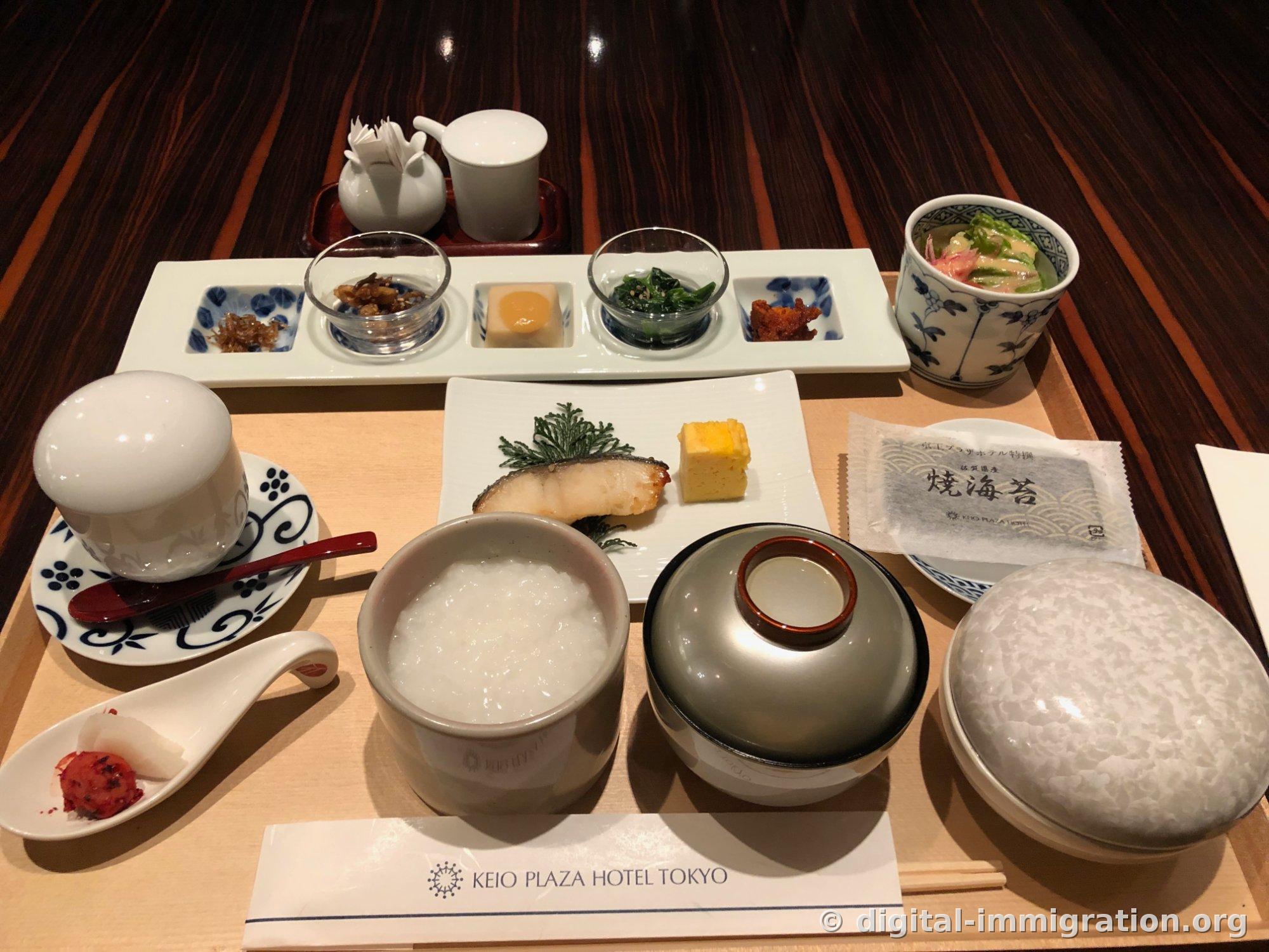 Plateau de petit-déjeuner japonais chez Kagari au Hôtel Keio Plaza. Les bols de riz, de soupe et de chawan-mushi sont couverts de couvercles, avec des algues nori cuites de Saga emballées individuellement, une assiette de cinq accompagnements, un poisson blanc grillé et une omelette roulée