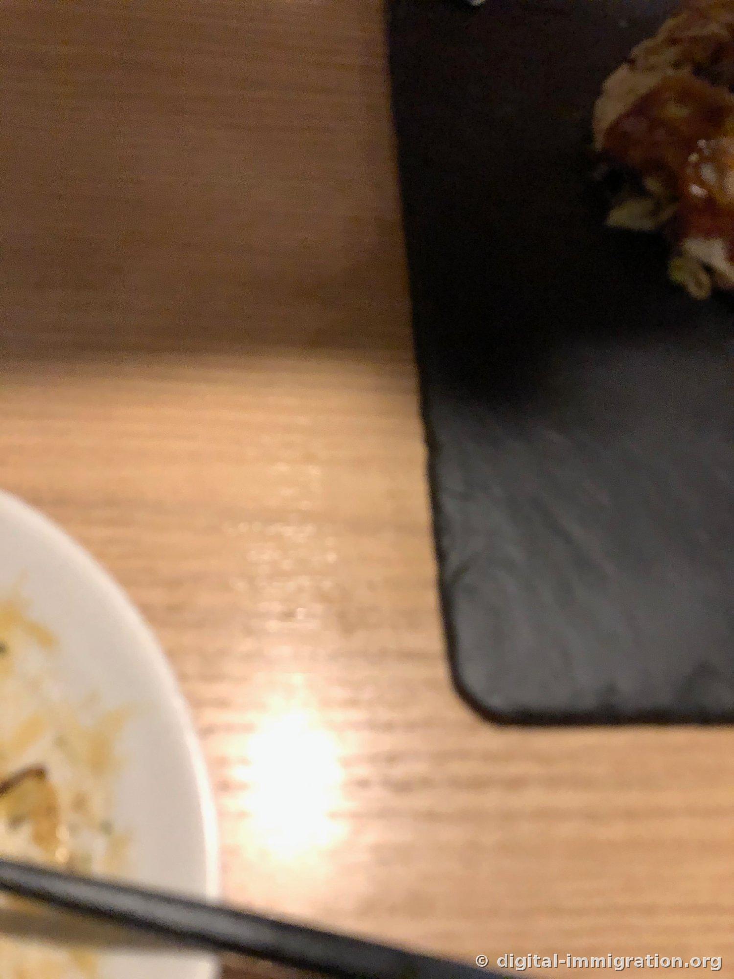 초점이 흐릿하게 나간 사진, 나무 테이블과 검은 슬레이트 접시 모서리, 비어가는 흰 앞접시