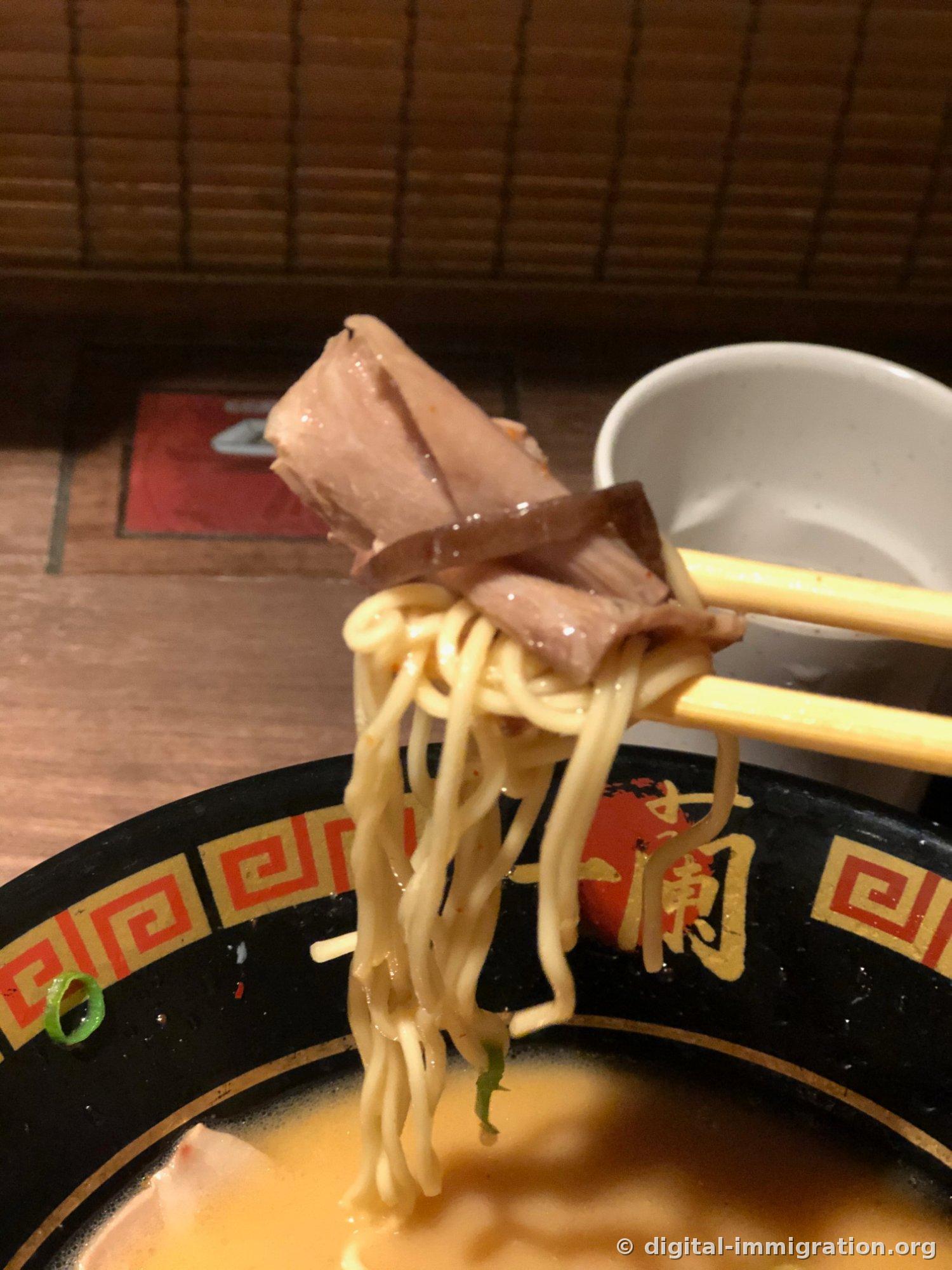 Des nouilles, du char siu et du kikurage tous accrochés ensemble aux baguettes