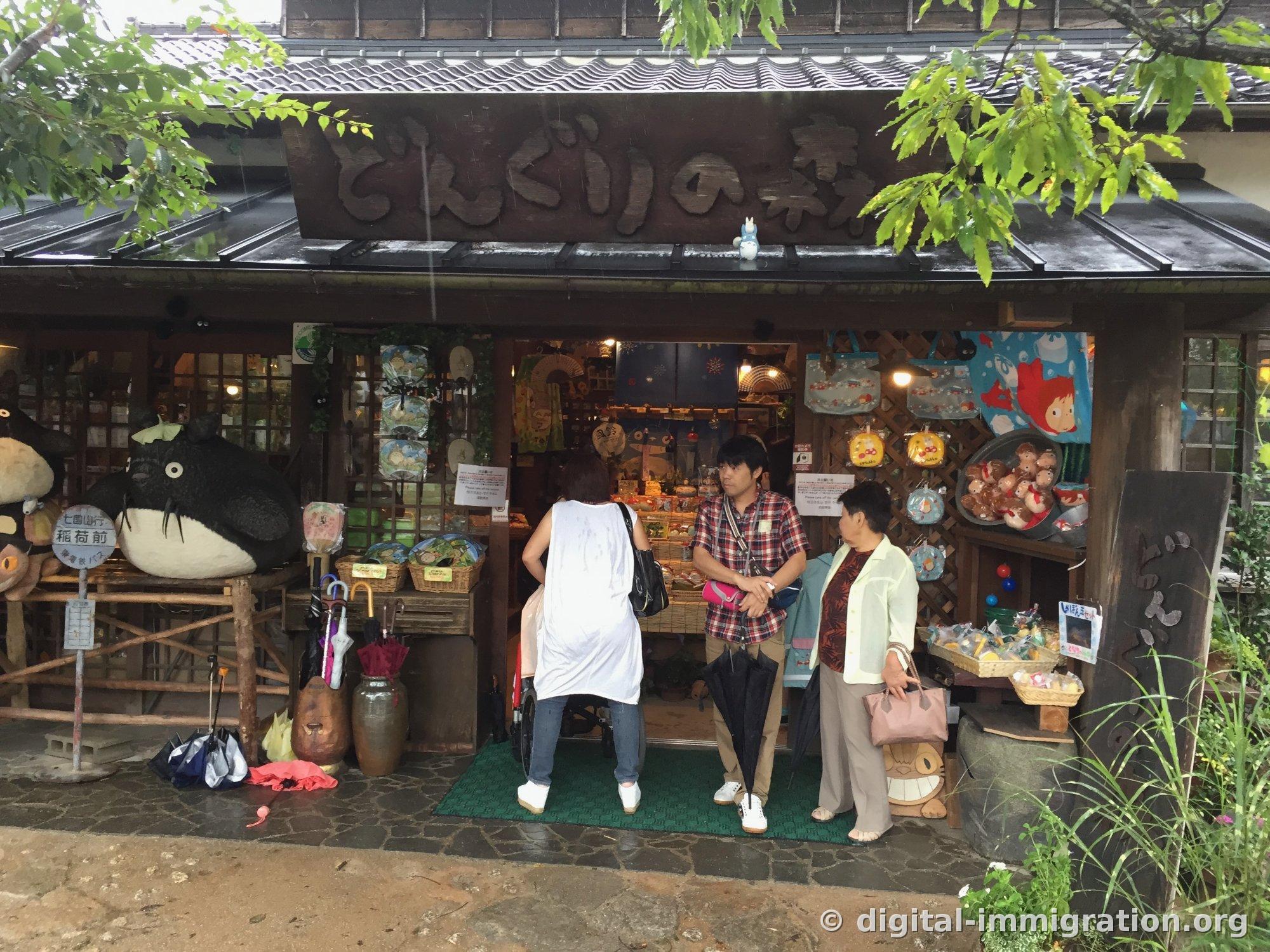 La façade du magasin どんぐりの森 avec des sacs Totoro et Ponyo accrochés au mur en treillis et un petit Totoro blanc sur l'avant-toit