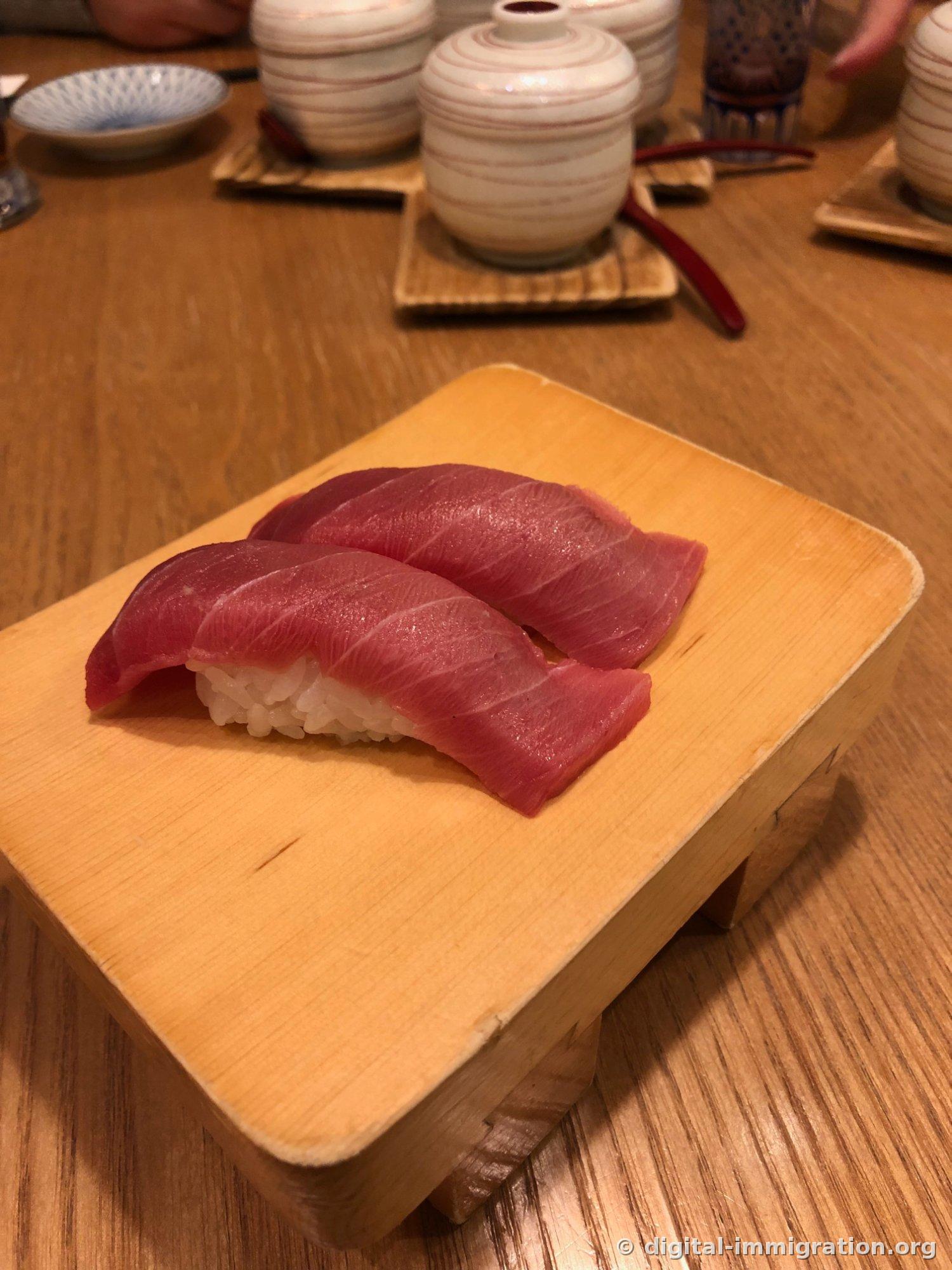 Gros plan des deux pièces de nigiri de chu-toro sur un support en bois. Les fibres du muscle rouge et de la graisse blanche sont clairement visibles