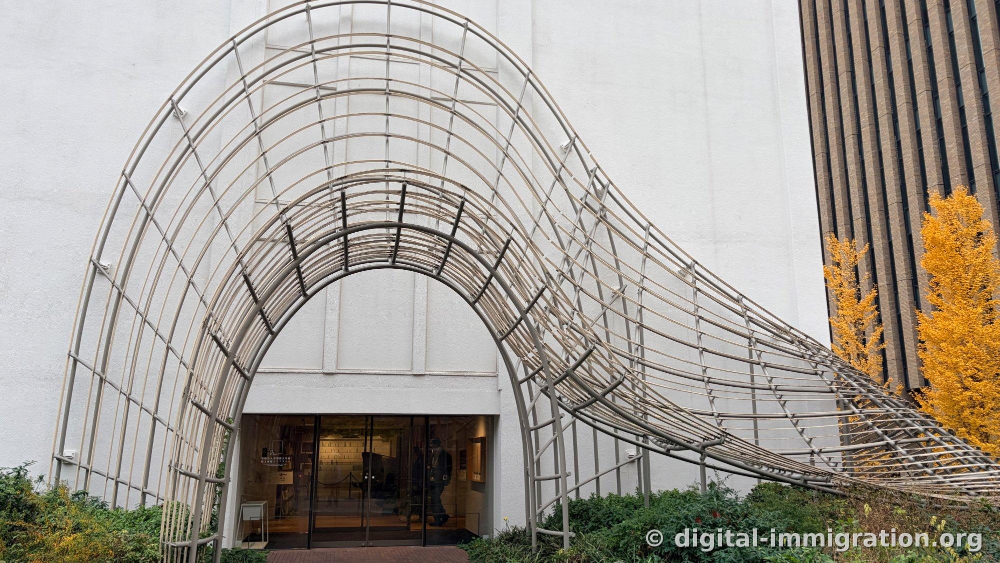 白色墙面上隧道形金属拱结构和下面玻璃门入口