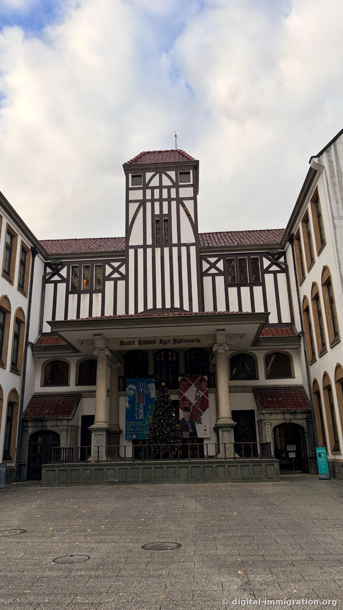 演剧博物馆正面竖向构图，门廊前装饰的圣诞树和展览横幅
