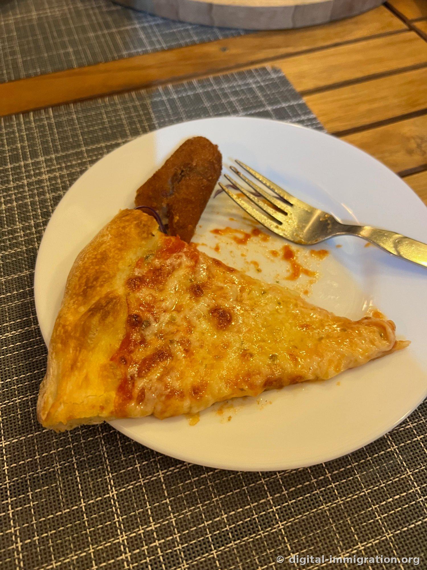 A white plate with a slice of tomato sauce pizza and a fried croquette, a fork beside it