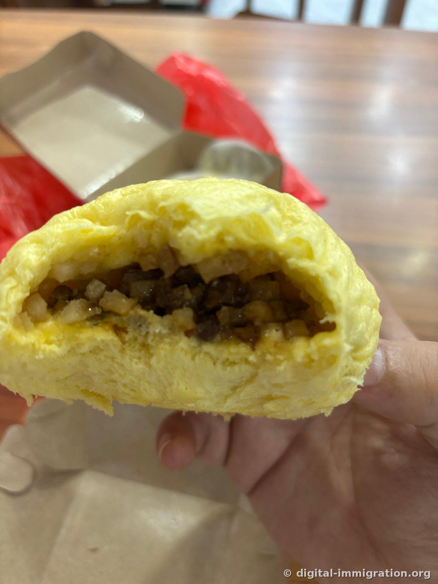 Section transversale du baozi à la courge jaune coupé en deux. L'intérieur est rempli de porc haché, de matière blanche en dés et d'huile