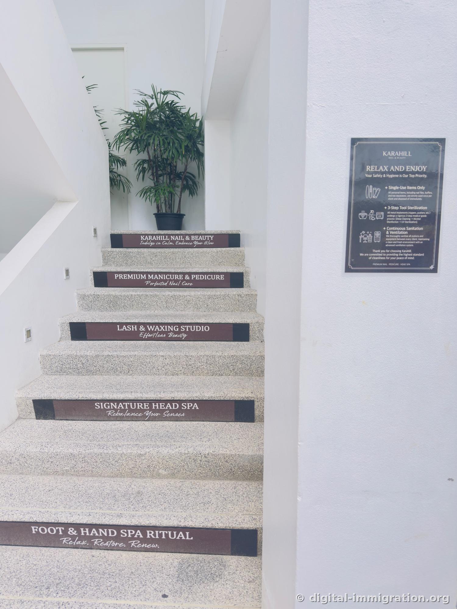 Menu signs on each step of the staircase (FOOT & HAND SPA RITUAL, SIGNATURE HEAD SPA, LASH & WAXING STUDIO, PREMIUM MANICURE & PEDICURE) and a hygiene notice poster on the right wall