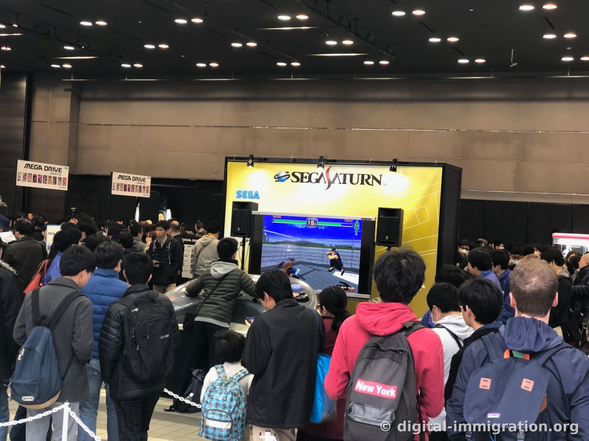 Spectators crowded in front of Sega Saturn-branded event booth with Virtual Fighter tournament screen