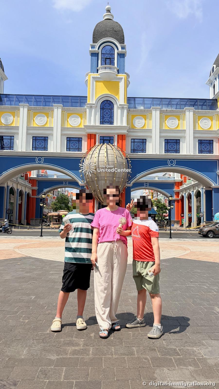 Three people standing in front of a blue and yellow arch gate with