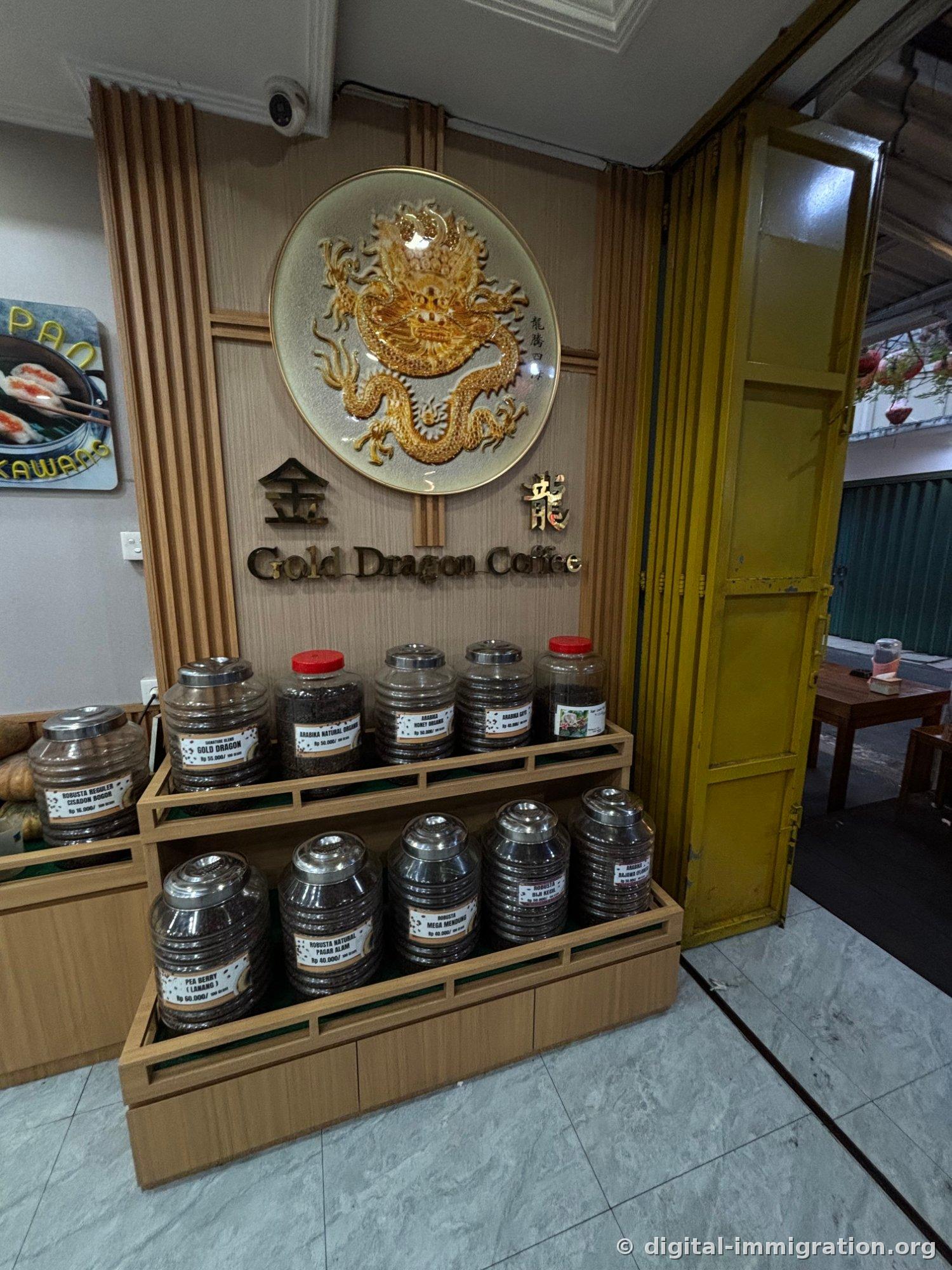 Assiette décorée avec dragon doré et enseigne 金龍 Gold Dragon Coffee, avec des bocaux en verre de grains de café sur une étagère en bois en dessous. Chaque bocal porte une étiquette avec le nom de la région et le prix