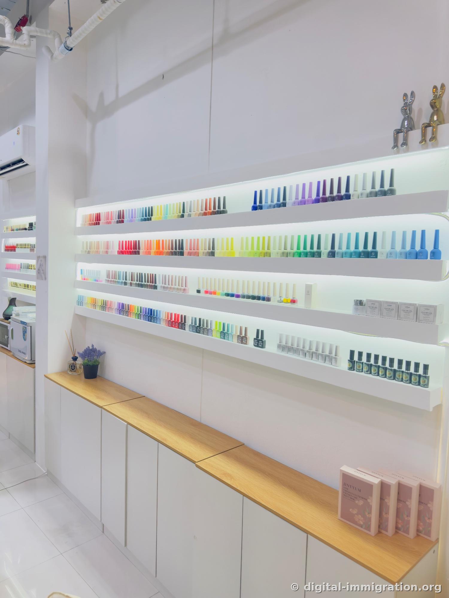 Four-tier illuminated shelves covering an entire wall, hundreds of gel polish bottles arranged by color, with silver and gold rabbit figurines at the end of the top shelf