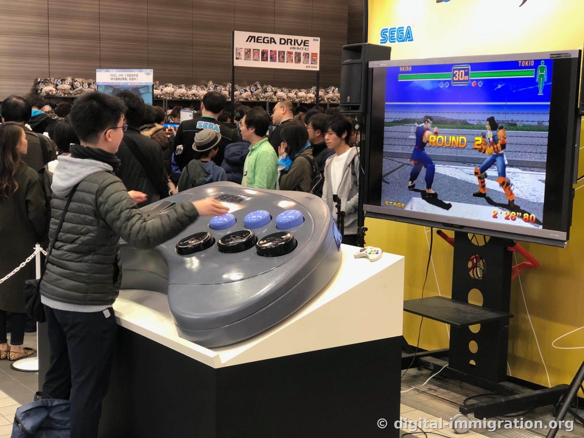 Spectator operating giant Mega Drive controller sculpture with Virtual Fighter ROUND 2 screen